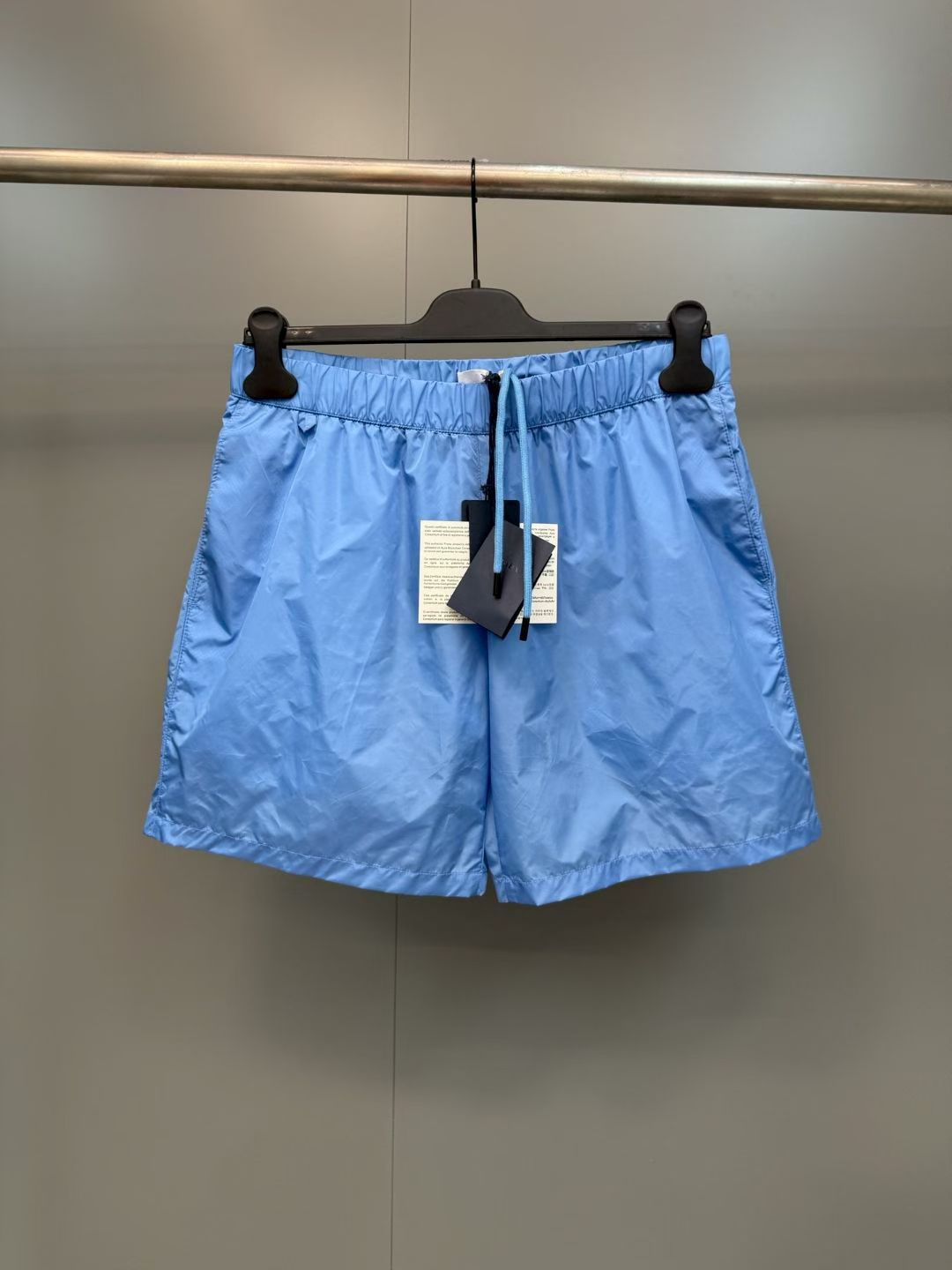 NO:852954,PRA metallic triangle logo contrast trim casual shorts  Made of specially imported recycled nylon fabric specially supplied by the brand, it has undergone special water-repellent treatment. It has a light and crisp texture with a soft matte texture. It has excellent breathability, wrinkle resistance and quick-drying performance. The upper body feels dry and comfortable, and has excellent drape and deformation resistance. The waistband is designed with high elasticity and is equipped with hidden drawstring adjustment. It fits the waist line without being tight, taking into account the convenience and comfort of daily wear. The trousers are neatly cut,  The trouser legs have been optimized for many times, with smooth lines that modify the shape of the legs. The straight-leg version is not flattering on the figure and is suitable for a variety of dressing styles. The edges of the trouser legs are made of double-thread seaming technology, with even and fine stitching, which is wear-resistant and durable. The overall process is rigorous, and every splicing and wiring is processed with precision. Details such as pocket reinforcement and waistband hemming are all double-reinforced. The brand's classic elements are perfectly integrated with modern functional design, taking into account both practical performance and fashionable style.  Material: nylon, loose fit, color sky blue/off-white/dark gray/bright red/black, Prada-clothing, prada, prada, shorts,19860909PRA 金属三角标撞色饰边休闲短裤 采用品牌特供进口再生锦纶面料,经过特殊防泼水处理,质地轻盈挺括且自带柔和哑光质感,兼具出色的透气性、抗皱性与速干性能,上身体感干爽舒适,同时拥有优越的垂坠度与抗变形能力；腰头采用高弹松紧设计,搭配隐藏式抽绳调节,贴合腰部线条且不勒不松,兼顾日常穿着的便捷性与舒适感；裤身剪裁利落利落,裤腿经过多次版型优化,线条流畅修饰腿型,直筒版型不挑身材,适配多种穿搭风格；裤脚边缘采用双线锁边工艺,针脚均匀细密,耐磨耐穿；整体工艺严苛,每一处拼接、走线均经过精密处理,口袋加固、腰头锁边等细节部位均采用双重加固工艺,将品牌经典元素与现代功能性设计完美融合,兼顾实用性能与时尚格调. 材质: 锦纶 版型宽松 颜色天蓝/米白/深灰/亮红/黑色,普拉达-服装,prada,prada,shorts,,Women's clothing