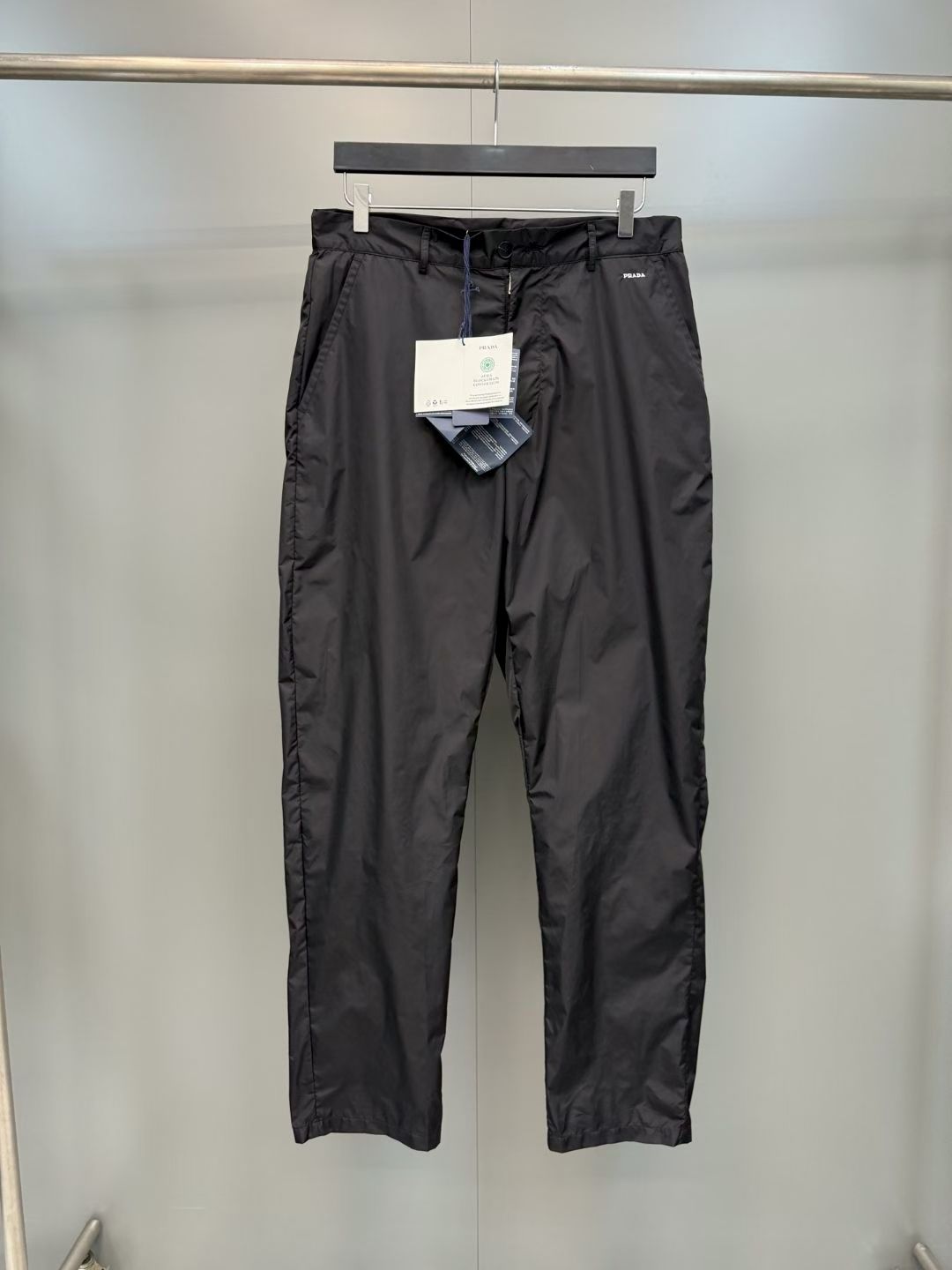 NO:852971,PRA simple logo embroidered trousers  Made of specially imported nylon fabric, the texture is light and smooth, feels skin-friendly and breathable, and has excellent wrinkle resistance, windproofness and drape, ensuring the quality and practicality of casual pants; the front is opened and closed with resin buttons of the same color, with high-quality texture, convenient opening and closing, and each button highlights the brand's exquisite craftsmanship; symmetrical design of oblique pockets on both sides, the bag shape is three-dimensional and crisp, and the wiring is neat and delicate, which not only facilitates the placement of personal belongings, but also enriches the structure of the pants; the waist  The right side of the head is embellished with the PRADA white brand letter embroidery logo. The embroidery is full and three-dimensional, the stitching is neat and delicate, and the craftsmanship is exquisite and eye-catching. It breaks the monotony of pure black, adds a sense of detailed design, and shows the brand recognition in a low-key manner; the trousers adopt a flat line design, with smooth and neat lines, strengthening the classic version of straight pants; the trousers adopt a flat edge design, the lines are neat and delicate, and they fit the body shape and are not easily deformed., Prada - Clothing, prada, prada,19860909PRA简约logo刺绣长裤 采用进口特供锦纶面料,质地轻薄顺滑,触感亲肤透气,兼具优异的抗皱性、防风性与垂坠感,保证了休闲裤的品质与实用性；正面采用同色系树脂纽扣开合,纽扣质感高级,开合便捷,每一颗都彰显品牌精致工艺；两侧对称设计斜插式口袋,袋型立体挺括,走线工整细腻,既方便放置随身物品,又丰富了裤身结构层次；腰头右侧点缀PRADA白色品牌字母刺绣标,刺绣饱满立体,针脚工整细腻,工艺精湛醒目,打破纯黑单调感,增添细节设计感,低调尽显品牌辨识度；裤身采用平整走线设计,线条流畅利落,强化直筒裤的经典版型；裤脚采用平整收边设计,走线工整细腻,贴合身形不易变形.,普拉达-服装,prada,prada,,Women's clothing