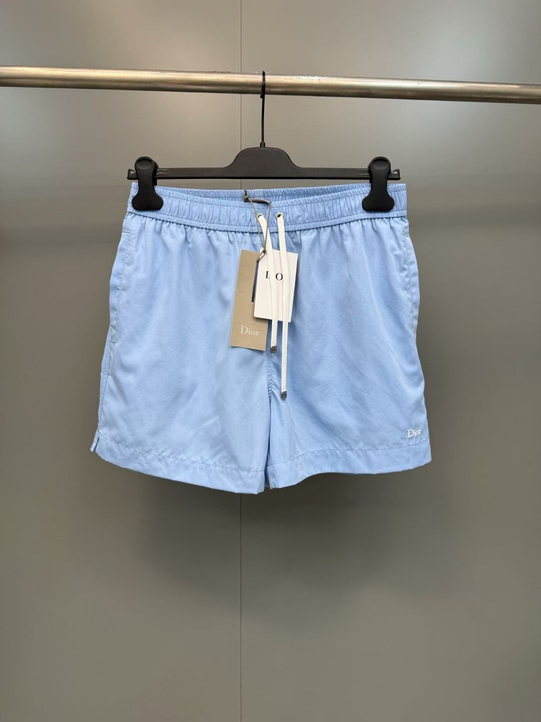 NO:852921,D's letter embroidered casual shorts  Made of brand-customized imported high-density nylon fabric, the texture is light and smooth. The waistband is designed with an elastic drawstring and matched with a metal-tipped drawstring of the same color. The tightness can be flexibly adjusted according to the waist circumference, adapting to a variety of body shapes. It is easy to put on and take off, taking into account both comfort and style.  It has a casual atmosphere; there are large-capacity pockets on both sides, and the lines are neatly routed, which not only ensures the practicality of item storage, but also adds casual details to the overall look; the sides of the pants are decorated with exquisite DIOR letter embroidery logos, and the embroidery process is delicate and smooth.  The stitching is even and firm, conveying the brand gene in a low-key manner, and becomes the finishing touch of the overall look; the trousers are straight cut with clean lines, and the loose and straight trousers have an excellent modification effect on the leg shape. The upper body and back are loose and stylish, and can be easily matched with T-shirts or sweatshirts every day to create a relaxed and advanced casual style; the simple and elegant navy blue and light blue colors are refreshing and versatile, and can be easily controlled whether it is daily travel, vacation, leisure or light sports scenes, showing a casual and design-rich fashion attitude.  Material: nylon, loose fit, color navy/light blue, Dior-clothing, dior, dior, dior, hoodie, sweatshirts, shorts, tees, t-shirt,19860909D家字母刺绣休闲短裤 采用品牌定制进口高密锦纶面料,质地轻盈顺滑,腰头采用松紧抽绳设计,搭配同色系带金属头抽绳,可根据腰围灵活调节松紧度,适配多种身形,穿脱便捷,兼顾了舒适感与造型的随性氛围；两侧设有大容量插袋,走线工整利落,既保障了物品存放的实用性,也为整体造型增添了休闲细节质感；裤身侧面饰有精致的DIOR字母刺绣标识,刺绣工艺细腻平整,针脚均匀牢固,低调传递品牌基因,成为整体造型的点睛之笔；裤脚采用平直剪裁,线条干净利落,宽松直筒的裤型剪裁,对腿型有着极佳的修饰效果,上身后松弛有型,日常搭配T恤或卫衣,都能轻松打造松弛又高级的休闲风格；简约大气的藏青与浅蓝配色清爽百搭,无论是日常出行度假休闲还是轻运动场景都能轻松驾驭,展现出随性又充满设计感的时尚态度. 材质: 锦纶 版型宽松 颜色藏青色/浅蓝色,迪奥-服装,dior,dior,dior,hoodie,sweatshirts,shorts,tees，t-shirt,,Women's clothing