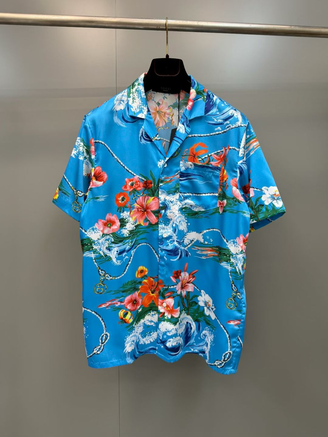 NO:857768,G's retro wave floral print casual short-sleeved shirt  It is made of high-definition mulberry silk blended fabric, tempered by multiple pre-shrinking and sand-washing processes. The texture is silky and smooth, skin-friendly and breathable, and feels warm and luxurious to the touch. The body of the garment is made of high-activity environmentally friendly digital direct-injection technology. The retro wave floral print on the front is delicate and lifelike. The waves, flowers, ropes and brand logo elements are rich and natural, and the color transition is soft and not harsh, perfectly restoring the brand logo.  Ideal holiday aesthetic atmosphere, the printing has been specially fixed and will not easily crack and fall off after long-term washing; the placket uses resin buttons of the same color, with brand details engraved on the button surface, which is smooth and durable; the cuffs adopt a single-button adjustment design, the routing is smooth and neat, and the cuffs can be adjusted at will., Gucci - Clothing, gucci, gucci, shirts, T-shirt,19860909G家复古海浪花卉印花休闲短袖衬衫 采用高定桑蚕丝混纺面料,经多重预缩与砂洗工艺淬炼,质地丝滑垂顺、亲肤透气,上手触感温润高级；衣身采用高活性环保数码直喷工艺,正面复古海浪花卉印花笔触细腻逼真,海浪、繁花、绳索与品牌标识元素层次丰富自然,色彩过渡柔和不生硬,完美还原品牌标志性的度假美学氛围,印花经特殊固色处理,久洗不易开裂脱落；门襟采用同色系树脂纽扣,扣面刻有品牌细节,开合顺滑耐用；袖口采用单扣调节设计,走线平整工整,可随心调整袖口松紧.,古驰-服装,gucci,gucci,shirts,T-shirt,,Women's clothing