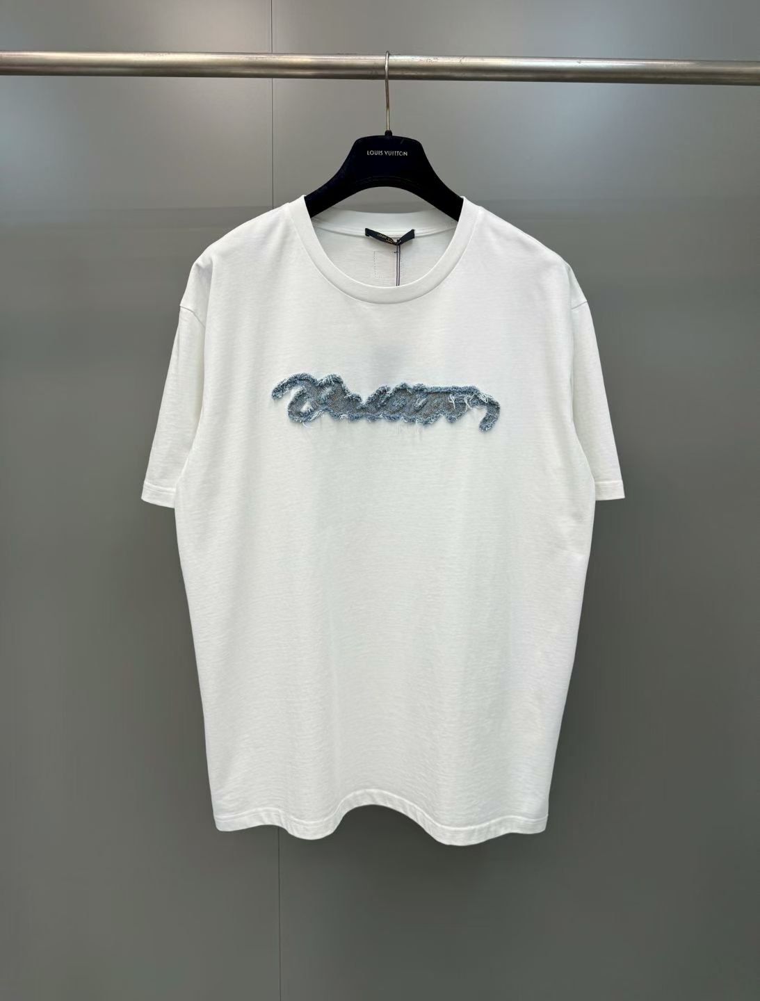 NO:867846,Lujia 26ss new patch-embroidered short-sleeved T-shirt is made from 210g heavyweight combed cotton jersey fabric and processed by garment washing process, giving the garment a soft and skin-friendly touch and a natural and soft retro texture, effectively improving the fabric's pilling resistance and dimensional stability  The body is cut with dropped shoulders, and is paired with a round neck and cuffs reinforced with two needles, taking both comfort and durability into account. The core decoration on the chest uses laser cutting patch + flat embroidery overlocking technology. The handwritten brand logo is accurately cut by laser, and the edges present a natural woolen effect. It is then fixed with contrasting stitching and flat embroidery. The edge of the patch is sanded and scattered, forming a rich three-dimensional raw edge effect. It has both craftsmanship details and visual tension. It is a model of the combination of street retro style and advanced garment technology.  Size S.M.L.XL.,Louis Vuitton-clothing,louis vuitton,louis vuitton,louis vuitton,T-shirt,tees,t-shirt,19860909驴家 26ss新款贴布绣短袖T恤,甄选210g重磅精梳棉平纹针织面料,经成衣水洗工艺处理,赋予成衣软糯亲肤的触感与自然柔和的复古质感,有效提升面料抗起球性与尺寸稳定性 衣身采用廓形落肩剪裁,搭配二本针加固工艺的圆领与袖口,兼顾穿着舒适度与耐穿性.胸前核心装饰采用激光切割贴布+平绣锁边工艺,手写体品牌标识经激光精准裁切,边缘呈现自然毛絮效果,再以撞色车线平绣固定,贴布边缘做磨毛散边处理,形成层次感丰富的毛边立体效果,兼具工艺细节与视觉张力,是街头复古风格与高级成衣工艺的结合典范 码数S.M.L.XL.,路易威登-服装,louis vuitton,louis vuitton,louis vuitton,T-shirt,tees，t-shirt,,Women's clothing