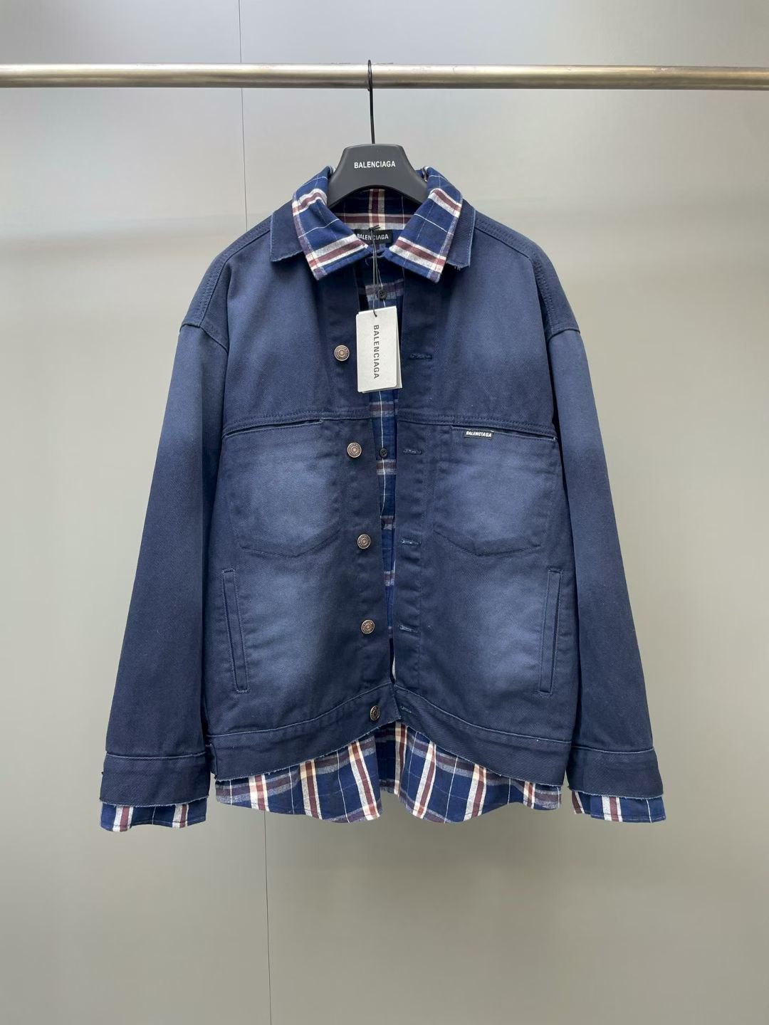 NO:867908,Paris fake two-piece plaid washed denim jacket  It is made of heavy-weight washed twill denim fabric, which has been treated with garment enzyme fading and whitening and distressed washing processes. The body of the garment presents a gradient navy blue smudged texture. The denim has a stiff frame while optimizing its softness, and the upper body does not feel stiff and abrasive; it adopts creative false pants.  A layered design, the outer layer is a classic lapel denim jacket style, and the inner layer is spliced with a red, brown and white vintage plaid shirt hem and collar, creating a layered look without additional matching, cleverly replicating the street layering trend; the collar uses subtle raw edge finishing details  , weakening the heavy feeling of tough denim and adding a casual retro atmosphere; the placket is equipped with a retro old metal round buckle, the buckle surface is treated with anti-oxidation coating, the texture is matte and fine, and the buckle spacing is regularly arranged; the front body is equipped with symmetrical double patch pockets and vertical pockets at the hem, and side chest pockets  The edges are embellished with the brand's micro-woven label, and the bag mouth is reinforced with multi-needle stitching, taking into account practical storage and workwear styling attributes; the combination of navy blue denim contrasting retro plaid is versatile, Balenciaga-clothing, balenciaga, jackets  & coats,shirts,19860909巴黎假两件格纹拼接水洗牛仔夹克 采用重磅水洗斜纹牛仔面料,经过成衣酵素褪色磨白与做旧水洗工艺处理,衣身呈现深浅渐变藏蓝晕染质感,牛仔挺括骨架的同时优化柔软度,上身无生硬磨肤感；采用创意假两件叠穿设计,外层为经典翻领牛仔夹克版型,内层拼接红棕白复古格纹衬衫衣摆与领口,不用额外搭配即可打造层次感穿搭,巧妙复刻街头叠穿潮流；领边采用细微毛边车工细节,弱化硬朗牛仔的厚重感,增添随性复古氛围；门襟配备复古做旧金属圆扣,扣面做抗氧化镀层处理,质感哑光细腻,扣距排布规整；前身配置对称双贴袋与下摆竖插袋,胸袋侧边点缀品牌微型织唛标识,袋口多针锁边加固,兼顾实用收纳与工装造型属性；藏蓝牛仔撞色复古格纹的组合百搭出彩,巴黎世家-服装,balenciaga,jackets & coats,shirts,,Women's clothing