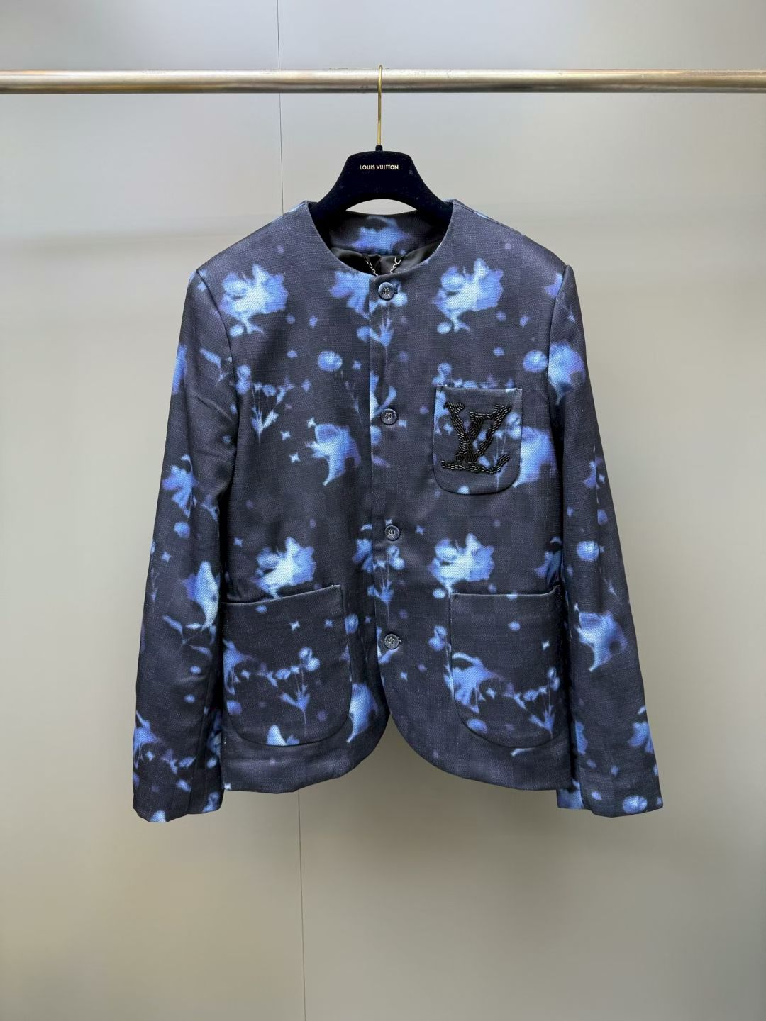 NO:888802,1V sfumato floral collarless blazer  Made of high-count blended twill fabric, treated with a special dyeing process, it presents a deep navy blue background with a gradient blue blooming floral pattern. The blooming effect is rich and natural, just like the hazy and elegant shadows of flowers in the fog. The fabric has both a crisp silhouette and a soft drape, making it comfortable, breathable and not easy to wrinkle. It adopts a collarless round-neck design with clean and simple lines, which weakens the toughness of traditional jackets and brings a relaxed and casual temperament. It has a single-breasted front closure with three buttons.  The matte buttons of the same color have a delicate and low-key texture; there are symmetrical pockets on both sides of the body, which are convenient for storing things and are both practical and beautiful; the loose straight fit is neatly cut, and the dropped shoulder design weakens the shoulder line, which is highly tolerant to different body shapes. It is casual and casual when worn alone, or layered with shirts or sweaters to easily create a multi-layered look; the overall style combines modern art blooming aesthetics and brand classic elements to break the monotony of traditional jackets., Louis Vuitton - Clothing, Louis  vuitton,jackets & coats,jackets & coats,shirts,198609091V晕染花卉无领西服外套 采用高支混纺斜纹面料,经过特殊定染工艺处理,呈现深邃藏青底色搭配渐变蓝色晕染花卉图案,晕染效果层次丰富过渡自然,如同雾中花影朦胧雅致,面料兼具挺括廓形与柔软垂坠感,穿着舒适透气且不易起皱；采用无领圆领设计,线条利落简约,弱化传统夹克的硬朗感,自带松弛随性的气质；正面单排扣开合,搭配三颗同色系哑光纽扣,质感细腻低调；衣身两侧设有对称插袋,方便置物且兼顾实用与美观；宽松直筒版型剪裁利落,落肩设计弱化肩线,对不同身形包容度高,单穿随性休闲,叠穿衬衫或针织衫也能轻松打造多层次造型；整体风格融合现代艺术晕染美学与品牌经典元素,打破传统外套的单调感.,路易威登-服装,louis vuitton,jackets & coats,jackets & coats,shirts,,Women's clothing