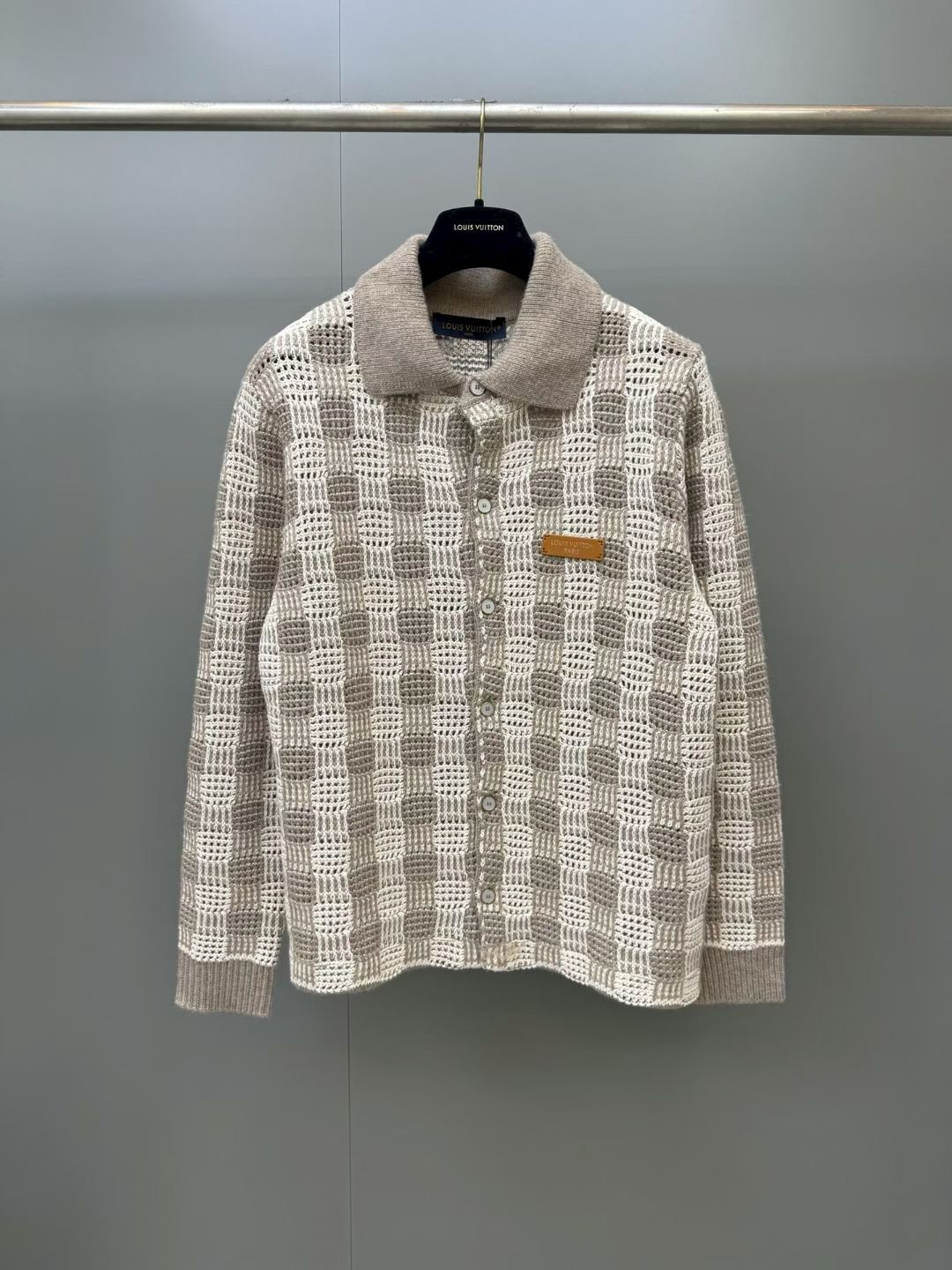 NO:951572,Lujia's 2026 new knitted plaid long-sleeved cardigan. This light beige cardigan is made of soft cotton blended yarn and decorated with exquisite hollow patterns. The style adopts a same-color plaid pattern, embellished with pearl-effect buttons, and is decorated with a unique natural cowhide patch on the chest and embellished with a gold brand logo. This light and elegant piece is perfect for creating a layered look and can add the finishing touch to summer outfits with this season's classic tones. The loose fit is beige.  Shirt-style collar Ribbed cuffs Jacquard checkered sweater with openwork Pearl-effect button fastening Leather patch with hot-stamped gold logo on the chest.,Louis Vuitton-Clothing,louis vuitton,louis vuitton,louis vuitton,shirts,cowhide,19860909驴家2026新款针织衫格子长袖开衫,这款浅米色开衫采用柔软的棉混纺纱线制成,饰有精致的镂空花纹.款式采用同色系格纹图案,点缀着珍珠效果纽扣,胸前则饰有独特的天然牛皮贴片,并缀有金色品牌标识.这款轻盈飘逸的单品,非常适合打造层次感造型,并能以本季经典色调为夏季装扮画龙点睛.宽松版型颜色米色 衬衫式领口 罗纹袖口 提花格纹针织衫,采用镂空工艺 珍珠效果纽扣开合 胸前饰有烫印金色标志的皮革贴片.,路易威登-服装,louis vuitton,louis vuitton,louis vuitton,shirts,cowhide,,Women's clothing