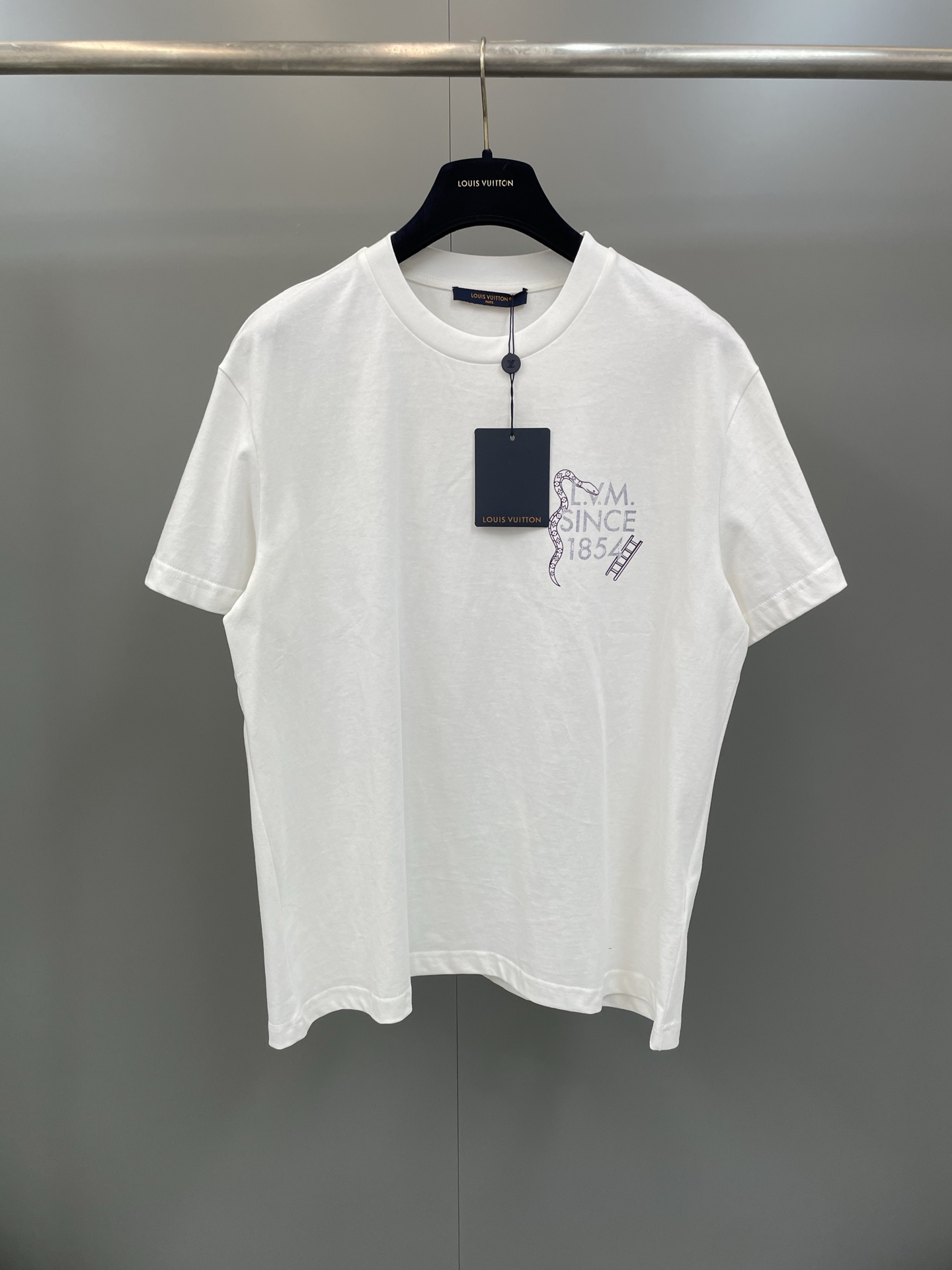 NO:775433,Donkey Family Snake Year logo short-sleeved fabric is made of 50-count double-strand mercerized cotton/165G, 32-count double-strand high-density ribbing/300G. This cotton T-shirt is decorated with interesting theme patterns from the 2026 spring and summer show. The new LV.M. logo is printed on the chest, surrounded by snakes and ladders decorated with Monogram patterns on both sides; on the back is Damier  The board game pattern is fully displayed on the checkerboard and is studded with the brand logo. It is made of silk-grade silk-smooth touch and feather-light fabric. The double-ply yarn structure significantly improves the tear resistance of the fabric. The mercerization treatment gives the fabric a pearl-like permanent luster and excellent color fastness. The neckline is matched with double-yarn high-density ribbing to build a collar support frame to ensure that the ultra-thin fabric maintains zero deformation of the collar shape in dynamic situations.  The board game pattern uses multi-color water-based ink digital direct printing technology, and the environmentally friendly ink is penetrated into the fiber marrow cavity through a 1440dpi ultra-high-resolution nozzle. This process enables the front and back patterns to achieve pixel-level alignment accuracy, and the color saturation reaches 98 degrees of restoration of the standard color card. It completely maintains the original breathability and softness of the fabric, and is washable and not easy to fade., Louis Vuitton-clothing, louis vuitton, louis vuitton, louis vuitton, louis  vuitton,T-shirt,tees,t-shirt,real silk,19860909驴家蛇年标识短袖 面料采用50支双股丝光棉 /165G,32支双纱高密罗纹 / 300G本款棉质T恤饰以 2026 年春夏秀场趣味主题图案.崭新LV.M.标识印于胸前,两侧环绕饰有 Monogram 图案的蛇与梯子；背部则在 Damier 棋盘格上完整呈现该棋盘游戏图案,并缀满品牌标识.采用真丝级滑糯触感与羽毛般轻盈体感的面料,双股纱线结构使面料抗撕裂强度明细提升,丝光处理赋予织物珍珠般的永久光泽与卓越色牢度.领口搭配双纱高密罗纹,构建领部支撑框架,确保超薄面料在动态中保持领型零变形. 棋盘游戏图案运用多色水性墨水数码直喷技术,通过1440dpi超高分辨率喷头将环保墨水渗透至纤维髓腔.该工艺使正反两面图案实现像素级对位精度,色彩饱和度达到标准色卡98还原度.完全保持面料原生透气感与柔软度,耐洗不易褪色.,路易威登-服装,louis vuitton,louis vuitton,louis vuitton,louis vuitton,T-shirt,tees，t-shirt,real silk,,Women's clothing