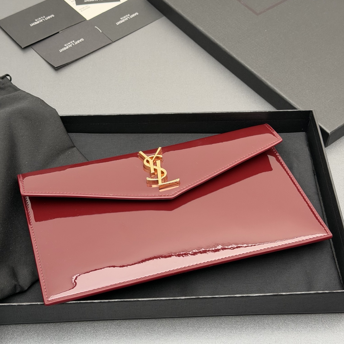 p350。【特级五金原厂皮】 UPTOWN漆皮皮革手拿包
小号信封手拿包，翻盖饰以金属字母标志
牛皮
金色金属配件
磁扣开合设计
内部一个主隔层
编号: 565739   枣红漆皮/金扣
尺寸:w27 xh16 xd2cm