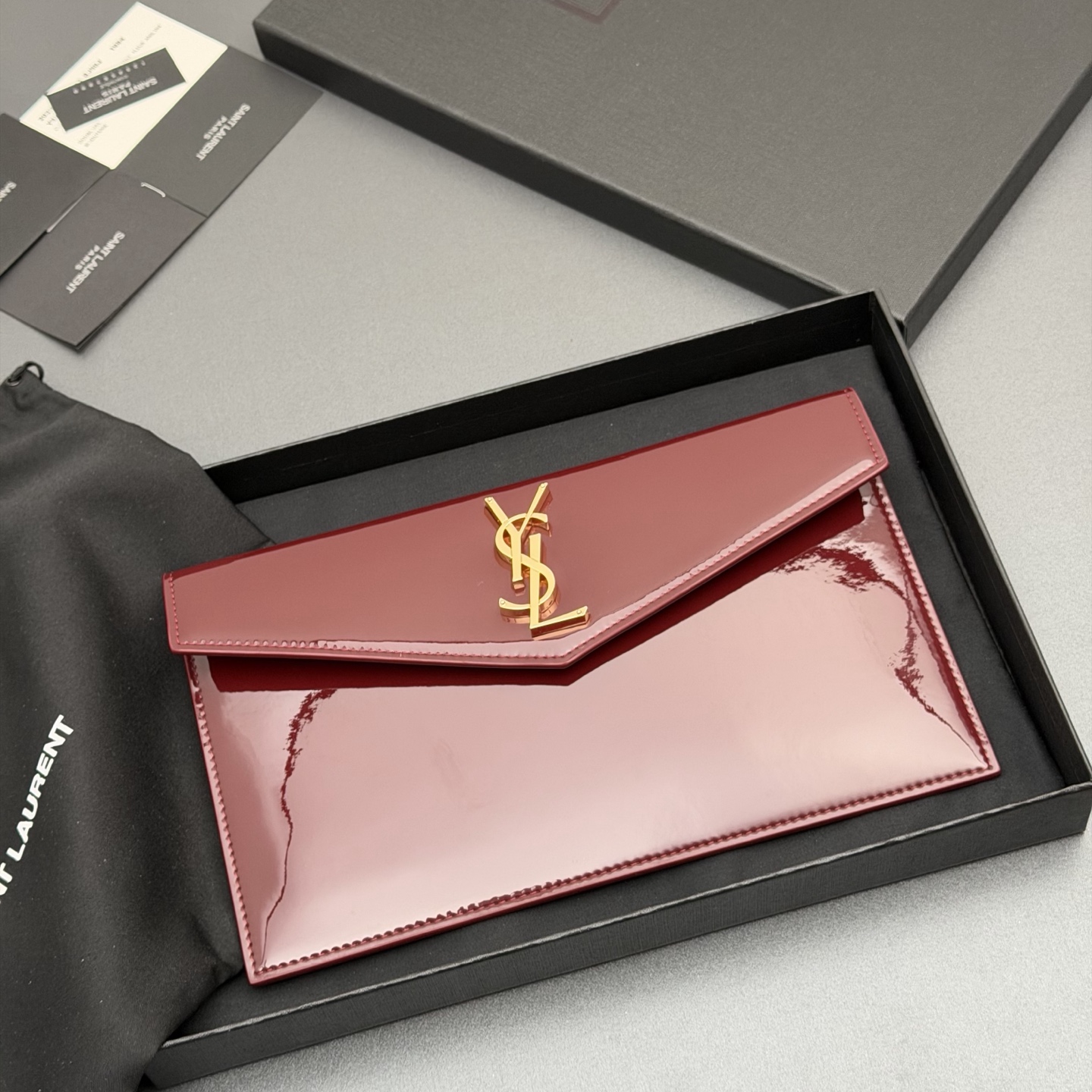 p350。【特级五金原厂皮】 UPTOWN漆皮皮革手拿包
小号信封手拿包，翻盖饰以金属字母标志
牛皮
金色金属配件
磁扣开合设计
内部一个主隔层
编号: 565739   枣红漆皮/金扣
尺寸:w27 xh16 xd2cm