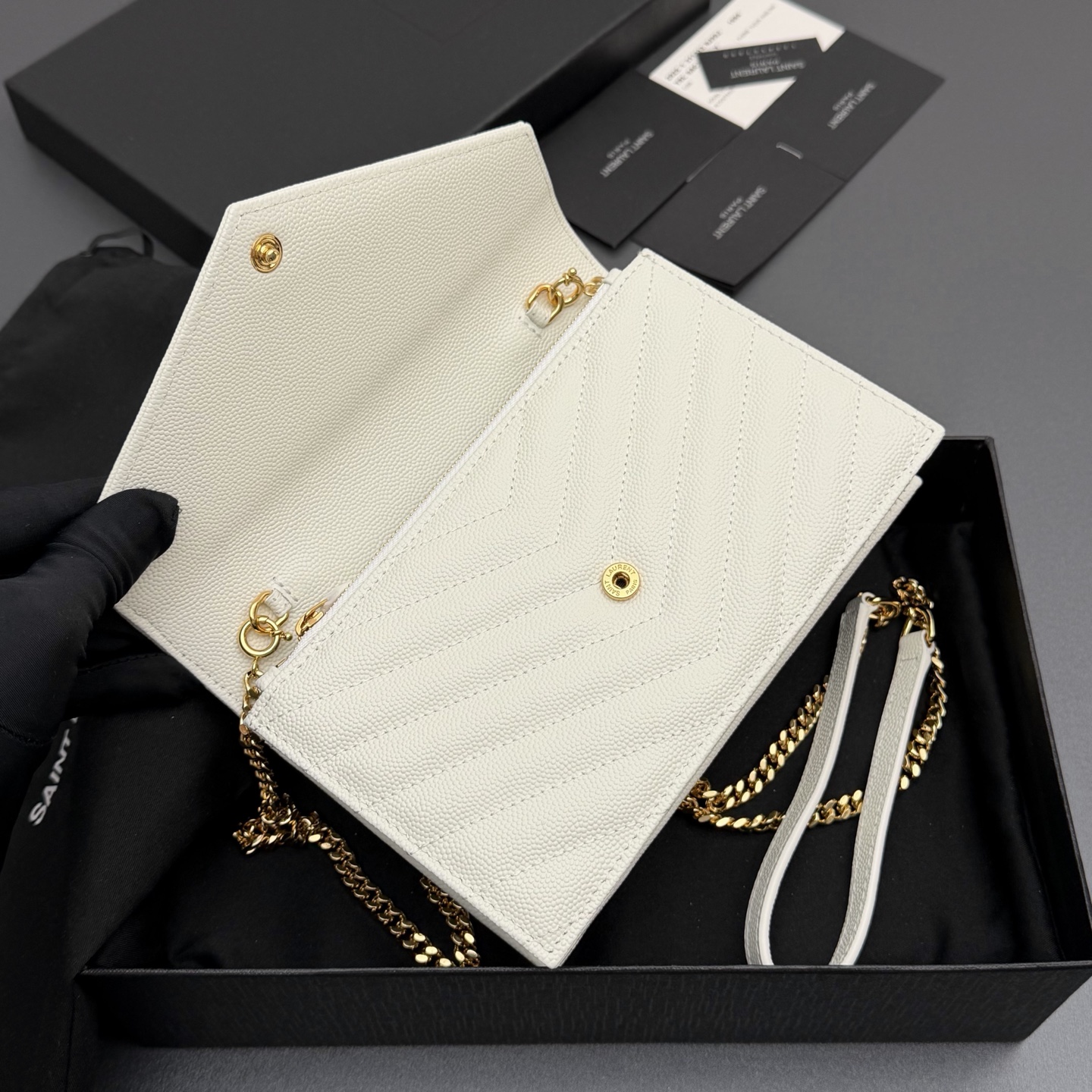 P470【特级五金原厂皮】ENVELOPE粒面皮革链条钱包
隽永链条钱包，标志性V形绗缝明缝线。实用性强，设有一个拉链口袋和多个卡槽。搭配皮革加固链接肩带，可肩背或斜挎携着。
牛皮
金色黄铜金属配件
按扣开合
六个卡槽
一个内部拉链口袋
编号: 393953 白色球纹/金扣
尺寸:w19xh12.5xd4cm