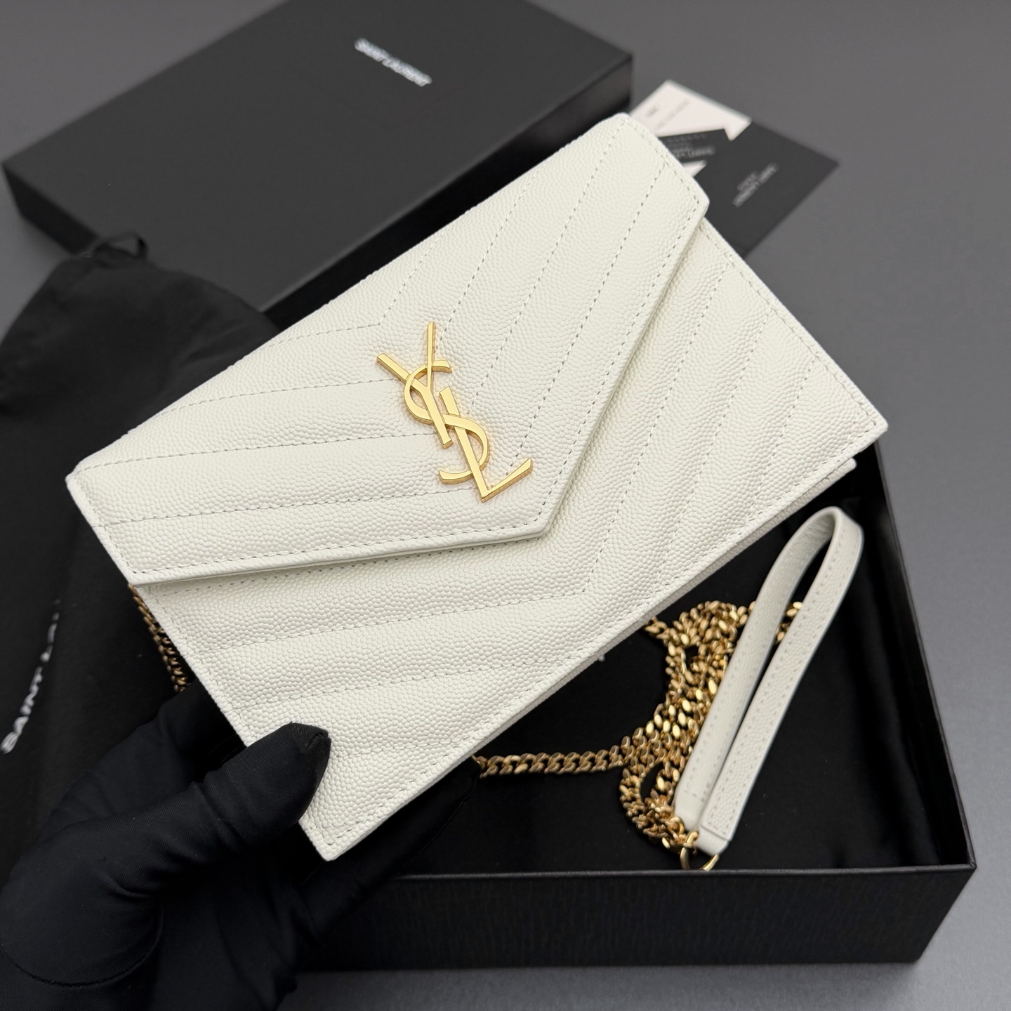 P470【特级五金原厂皮】ENVELOPE粒面皮革链条钱包
隽永链条钱包，标志性V形绗缝明缝线。实用性强，设有一个拉链口袋和多个卡槽。搭配皮革加固链接肩带，可肩背或斜挎携着。
牛皮
金色黄铜金属配件
按扣开合
六个卡槽
一个内部拉链口袋
编号: 393953 白色球纹/金扣
尺寸:w19xh12.5xd4cm