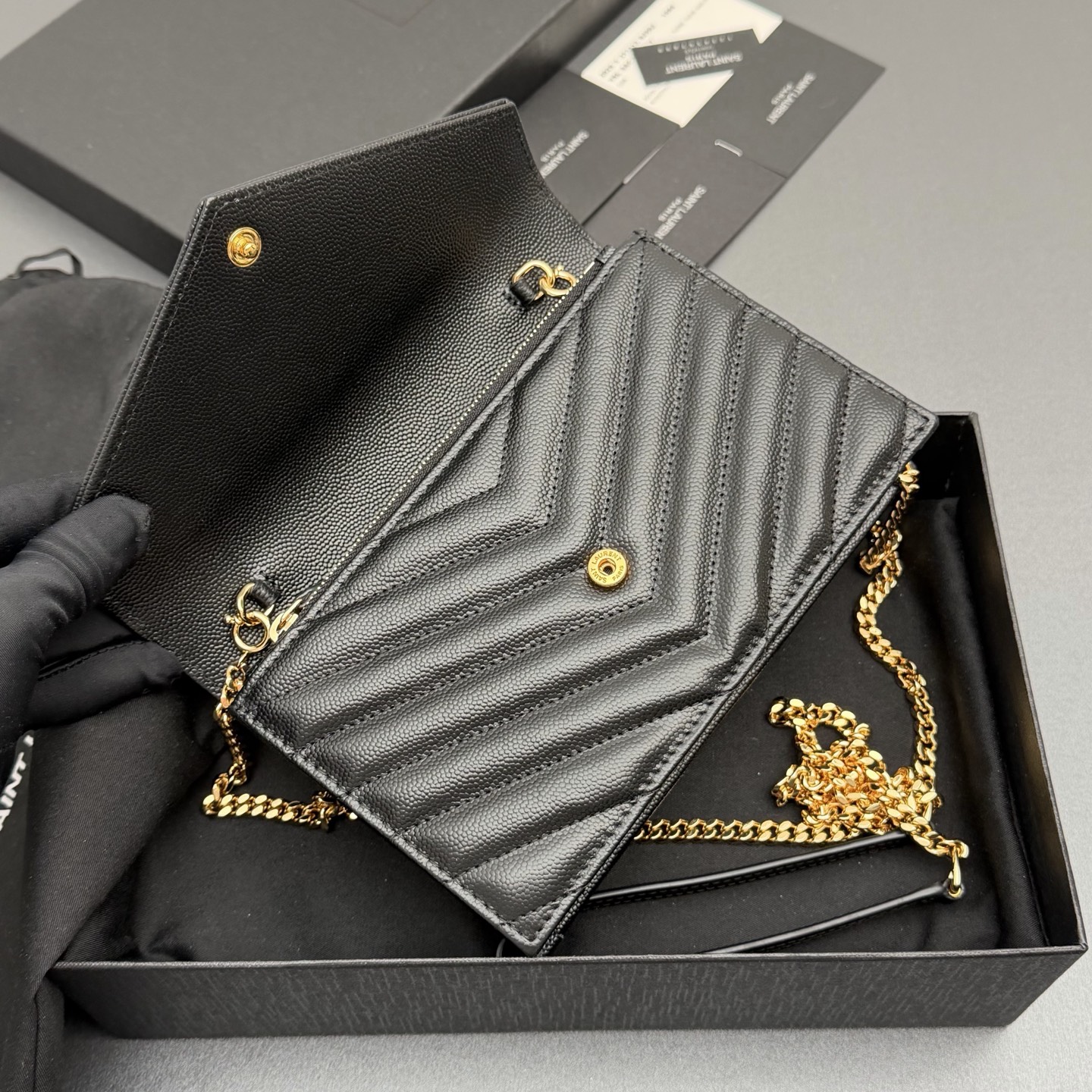 P470【特级五金原厂皮】ENVELOPE粒面皮革链条钱包
隽永链条钱包，标志性V形绗缝明缝线。实用性强，设有一个拉链口袋和多个卡槽。搭配皮革加固链接肩带，可肩背或斜挎携着。
牛皮
金色黄铜金属配件
按扣开合
六个卡槽
一个内部拉链口袋
编号: 393953 黑色球纹/金扣
尺寸:w19xh12.5xd4cm