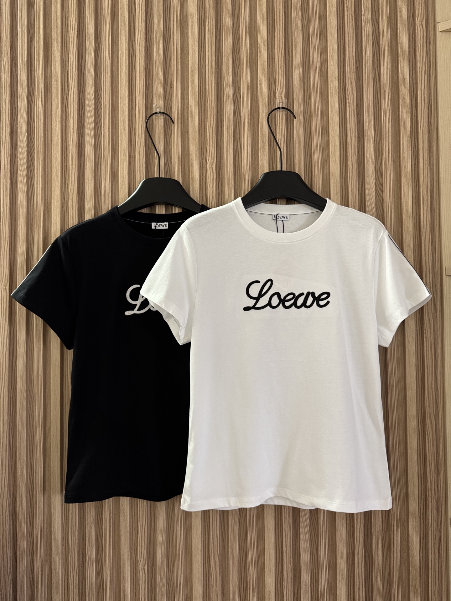NO:747975,Loewe 26 new spring and summer letter embroidery contrasting color thread hemming short-sleeved T-shirt Exclusive high-end production!  The letter embroidery on the chest is three-dimensional and full, and the lines are neat and not off-line; the contrasting thread seam design is both decoration and reinforcement, making the simple version instantly recognizable. The black and white two-color suit various skin colors and styles, and the slim tailoring modifies the body shape. It is refreshing and neat when worn alone, and layered to show more layering. It is the finishing touch to enhance the texture of the outfit!  Two-color SML,,loewe,T-shirt,tees,t-shirt,19860909Loewe 26春夏新款 字母刺绣撞色线锁边短袖T恤 独家高版出品！胸前字母刺绣立体饱满,走线工整不脱线；撞色线锁边设计,既是装饰也是加固,让简约版型瞬间有了辨识度.黑白双色适配各种肤色与风格,修身剪裁修饰身形,单穿清爽利落,叠穿更显层次,是提升穿搭质感的点睛之笔！两色SML,,loewe,T-shirt,tees，t-shirt,,Women's clothing
