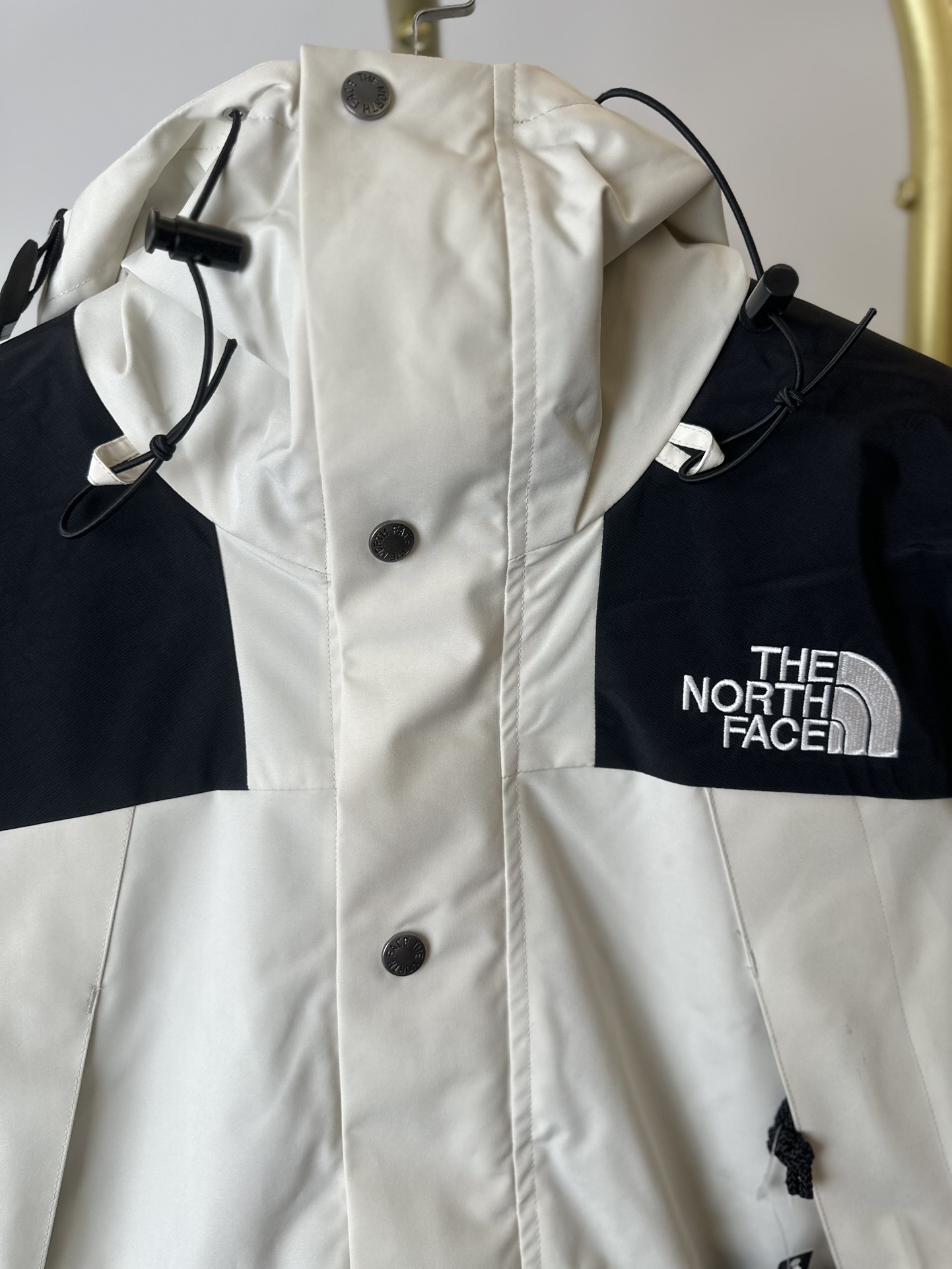 本地() THE NORTH FACE/北面 22FW MOUNTAINJACKETGTX 1990冲锋衣(米白) 带来90年代的功能性风格 美版1990GTX冲锋衣 距离山顶2KM的时候 脱下保暖内胆和背包 向山顶冲刺 所以起名“冲锋衣” 2L双层GORE-TEX面料 面料表层做强度防水 内层已经覆膜 所以到达实现三层防水的效果 使成衣具有防水透气的出色户外效果 领标附加一张以及袖口刺绣证明GORE-TEX面料身份 内衬冲锋衣面料属于功能性面料 防风防水内里设计 上半部分抓绒内里 下半部分尼龙内里 适用温度18°~零下20° 美版为细绒面的棉布内衬塔夫绸和拉绒经编衬里防风面料 质感厚实穿着舒服 薄薄的单层日版单层穿着感会差很远有点像雨衣般 单层的GTX在外观上也会大打折扣容易皱 拼接上幅拉绒面料设计 下幅尼龙面料设计 腋下有通风拉链的设计户外攀登滑雪越野作业时候实现温度自我控制的目的 田岛刺绣工整立体 饱满度立体感以及每个字母的神韵特点 一笔一划工工整整立体效果强烈 正面+背面+肘部贴片和袖口上的标志性色块和织物阻挡提供了高可见度和增加的耐用性