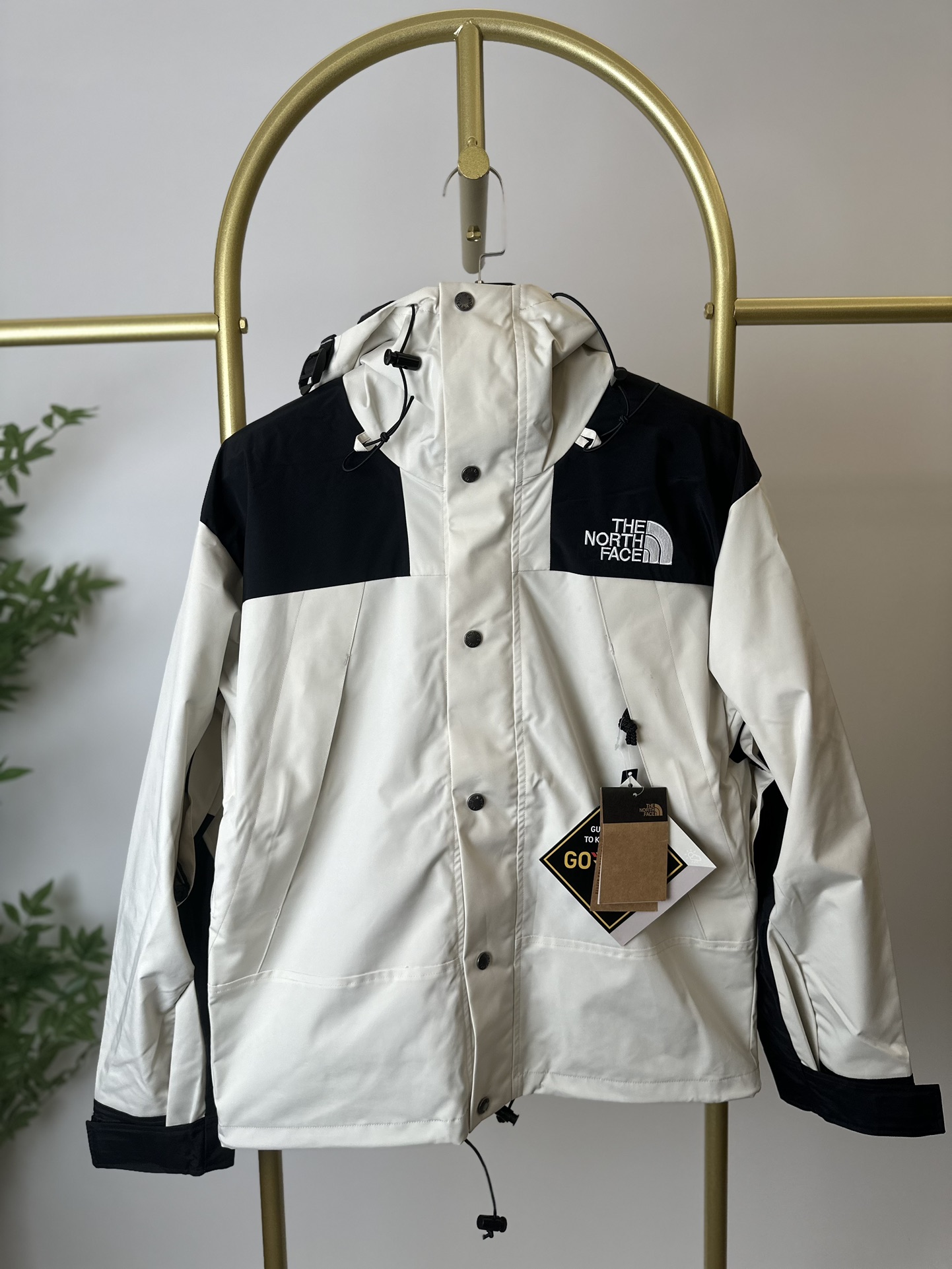 本地() THE NORTH FACE/北面 22FW MOUNTAINJACKETGTX 1990冲锋衣(米白) 带来90年代的功能性风格 美版1990GTX冲锋衣 距离山顶2KM的时候 脱下保暖内胆和背包 向山顶冲刺 所以起名“冲锋衣” 2L双层GORE-TEX面料 面料表层做强度防水 内层已经覆膜 所以到达实现三层防水的效果 使成衣具有防水透气的出色户外效果 领标附加一张以及袖口刺绣证明GORE-TEX面料身份 内衬冲锋衣面料属于功能性面料 防风防水内里设计 上半部分抓绒内里 下半部分尼龙内里 适用温度18°~零下20° 美版为细绒面的棉布内衬塔夫绸和拉绒经编衬里防风面料 质感厚实穿着舒服 薄薄的单层日版单层穿着感会差很远有点像雨衣般 单层的GTX在外观上也会大打折扣容易皱 拼接上幅拉绒面料设计 下幅尼龙面料设计 腋下有通风拉链的设计户外攀登滑雪越野作业时候实现温度自我控制的目的 田岛刺绣工整立体 饱满度立体感以及每个字母的神韵特点 一笔一划工工整整立体效果强烈 正面+背面+肘部贴片和袖口上的标志性色块和织物阻挡提供了高可见度和增加的耐用性
