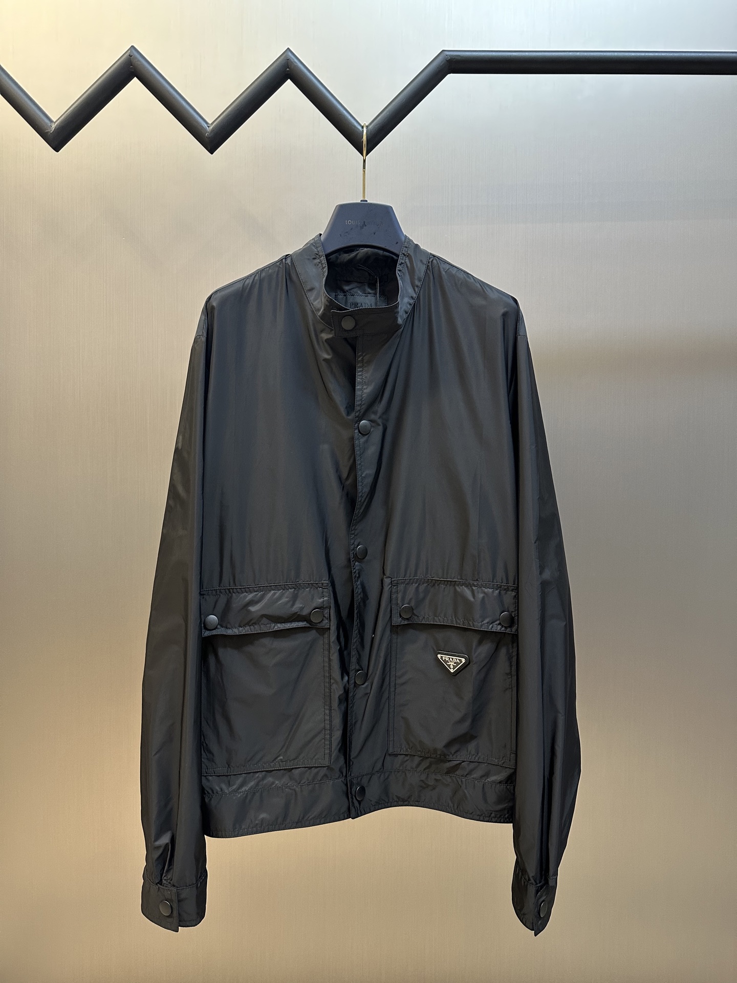 La chaqueta de nailon regenerado PRADA utiliza el icónico tejido de nailon regenerado de la marca, que tiene el mismo r…
