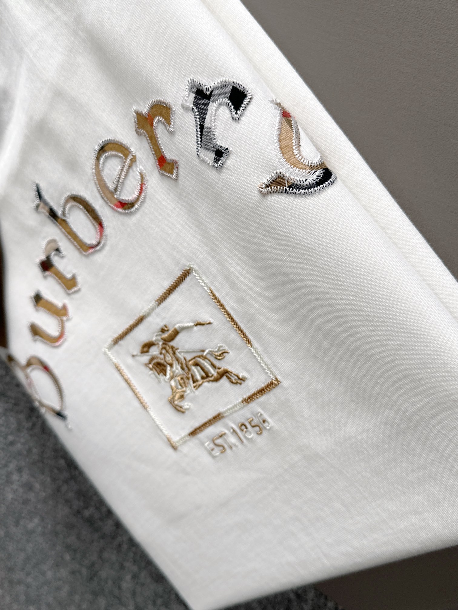 P85

Burberry 巴宝莉 BBR 2026新款 格纹布贴布刺绣战马logo oversize宽松版型 男女同款 短袖t恤
&middot;定制260克100％双纱纯棉面料
&middot;定染32支双股螺纹
&middot;领标吊牌主唛三标齐全
颜色：白色
尺码：S M L XL