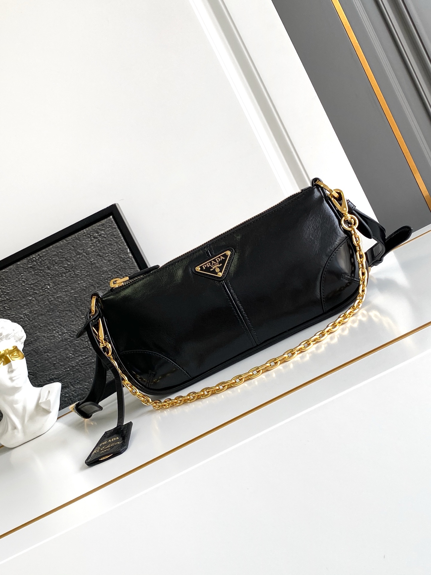 Prada 新款腋下包这款腋下包是2002年 款式的 版 而极简的配饰选用具有 光泽表面的皮革制成