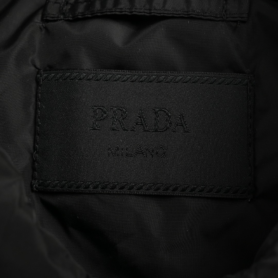 本地自取💰380 Prada 普拉达 24FW 口袋三角标棉服外套 面料定制高密度尼龙面料，内里充棉克重一致。虽然全幅没有图案Logo，但是我想经典的三角标标识已经够有辨识度了，实物太有质感太舒服了，上身休闲随意的感觉真的非常适合这个季节，随便一搭毛衣或卫衣又非常的酷飒，上身棉服内里加厚，版型Os风格，黑白真的很百搭。进口机器车缝，整体走线拼接处干净整洁，线距密度均匀一致，顶级混穿级别。五金开模全钢电镀，三角标字体精雕配十字纹皮牌，纽扣拉链细节尺寸颜色。 尺码：S-XL