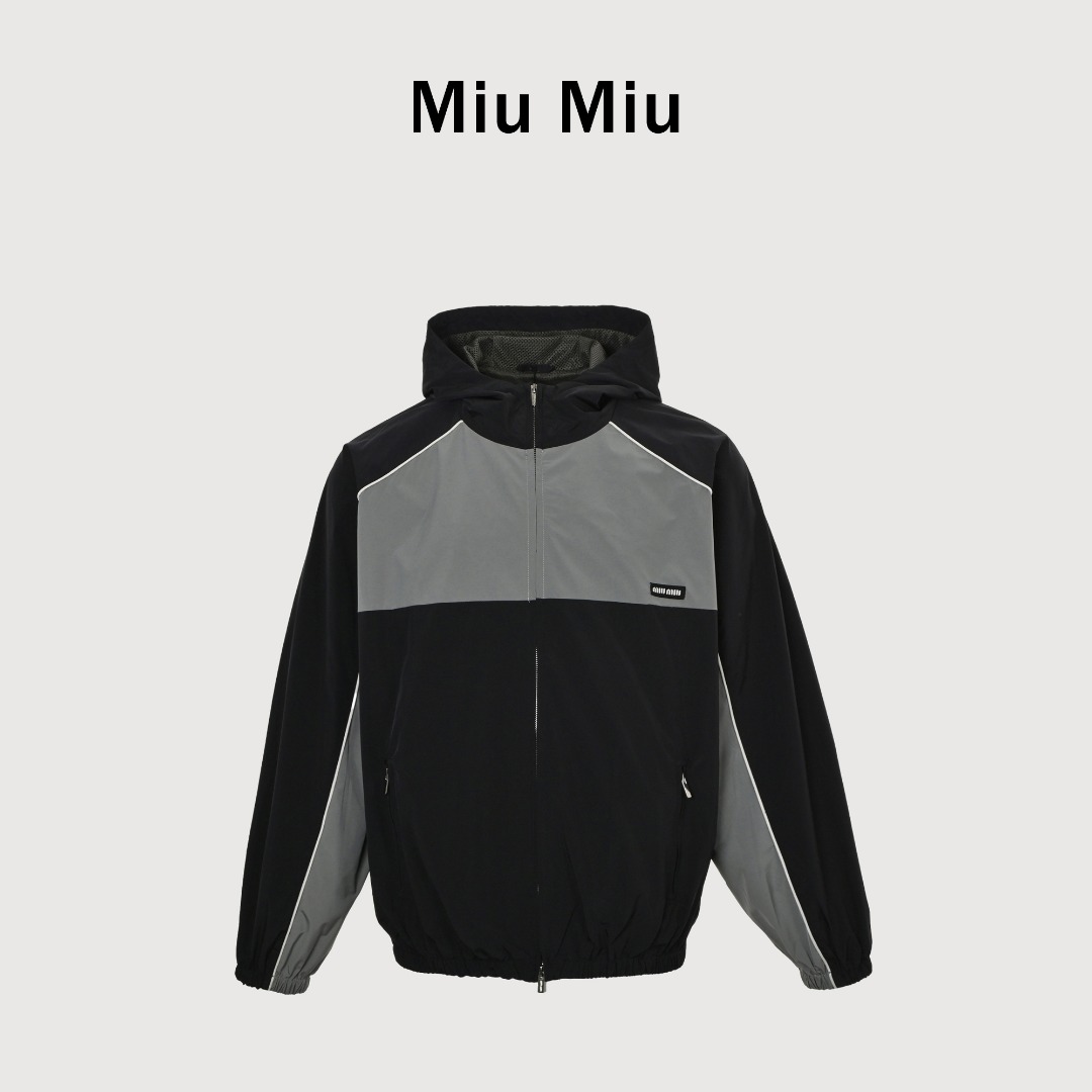 Miu Miu 25ss Miu小标藏青灰绿拼色梭织外套 面料梭织拼色主体,高密尼龙塔丝隆,采用30D/72超细旦纱线,经平纹+斜纹复合织造,表面做耐久防泼水涂层处理,可日常生活防水,正确版藏青色+灰绿色,并非纯黑拼接,注意甄别,激光切割拼缝剪裁,色块接缝处采用0.1mm级精密切割以热风压胶条,内衬加固.定制弹力捆条选用210T涤纶四面弹,经预缩处理后以45°斜裁包边,边缘采用三针五线收口,确保拉伸不变形,定织提花织带,以32股高强涤纶长丝织造,表面呈现Miu专属提花Logo,通过纱罗组织实现透气镂空.米色动态调节抽绳,双通道抽绳管,可单手调节,绳扣内部设微型棘齿结构,防止运动中松动,内里采用立体冲孔网布,以5mm厚度+70%开孔率的聚酯单丝编织,背部复合吸湿速干氨纶,定制五金定制合金拉链,链齿采用亮光氧化锆陶瓷,拉头内嵌双轴承滑轮,顺滑度达20,000次测试无卡顿