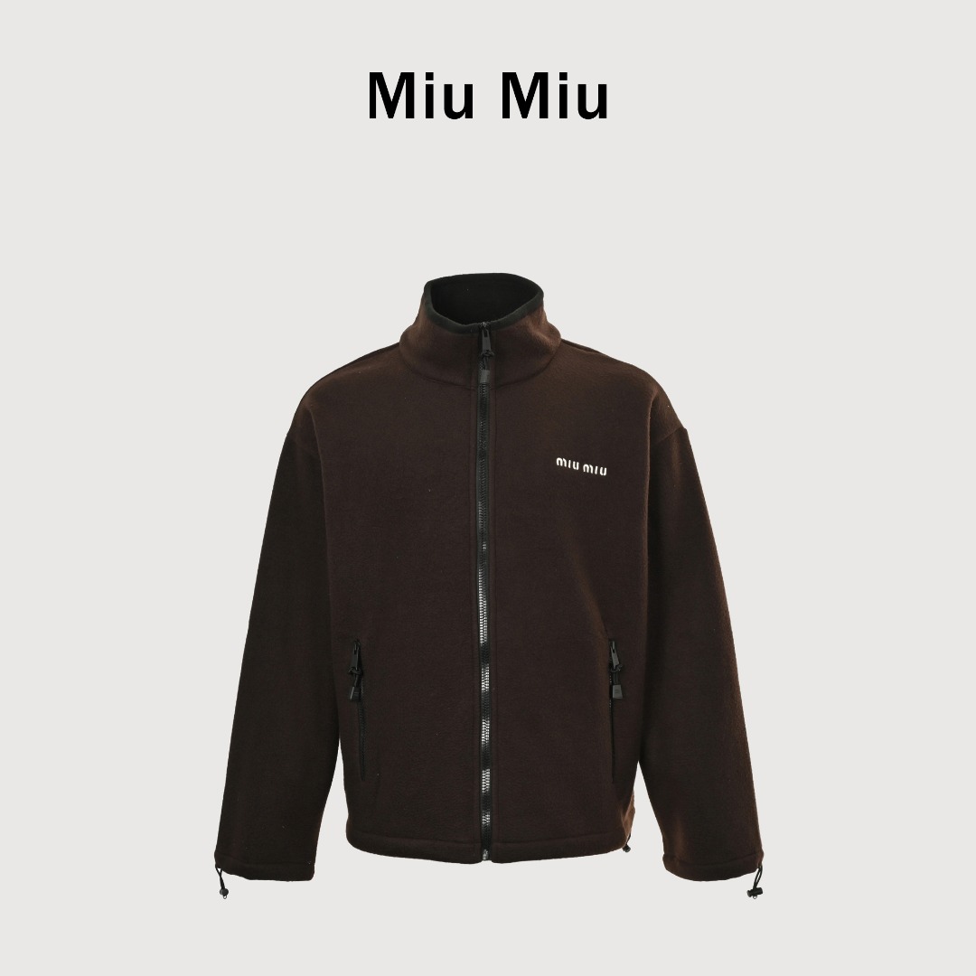 Miu Miu 25Fw Miu小标咖色摇粒绒立领外套 面料采用定制织造染整一体工艺,从纱线选配到染色均按品牌标准定制.400克重摇粒绒需平衡蓬松度与垂感,通过经纬密优化确保厚度一致且抗风保暖.色牢度控制:定染环节采用环保活性染料,经5次水洗测试确保色彩零偏差,实现桃粉、薄荷绿等高饱和度色调的纯净度.肌理处理:双刷双摇工艺打造绒毛丰盈且定向倒伏的立体质感,避免传统摇粒绒的臃肿感.全件拉链及配件均为开模定制,非市场公版零件.拉链齿工艺:采用哑光涂层YKK EXCELLA系列,顺滑度与耐久度超越工业标准,拉头内部结构加入消音硅脂.挂绳挂件设计:拉链片与挂绳采用超声波切割无缝拼接,尾端缀以激光雕刻Logo的锌合金吊坠,单挂件经历12道冲压打磨工序.装饰刺绣均采用田岛多针头绣花机完成.3D立体绣法:先以平绣打底,再叠加链目绣与毛巾绣混合工艺,使图案凸起高度达1.2mm,触感柔软不硌肤.本品以工艺冗余度换取极致体验,从纱线定制到终端装配均执行高精度标准,将功能性细节转化为隐性奢华,重构时尚单品的价值维度
