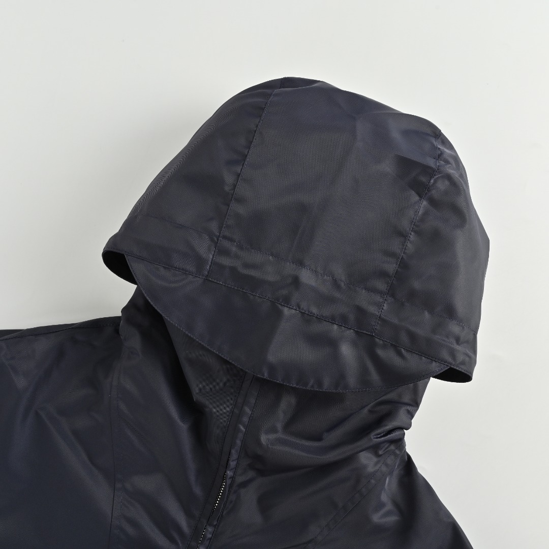 GUCCI古驰GUC 斜纹尼龙防风领连帽外套 选用100%锦纶纤维紧密编织而成的蓝色密织斜纹尼龙面料.经纬纱线之间的空隙非常小,表面呈现清晰的45度角斜向纹理.锦纶突出的耐磨性,抗拉扯等优点使成衣增加使用寿命.较小的密度强化防风性,同时兼具一定的防水性能,在室外能更好的发挥其功能性. LOGO刺绣贴饰采用0.3毫米超细聚酯绣线,经激光切割定型工艺打造浮雕质感.每片贴饰经过5道抗皱处理,确保水洗后仍保持原有形态. False Two-Piece设计增添层次感和独特性,采用高端隐形暗扣将帽子部分和大身链接一体,独立完整的双层结构,单穿叠穿皆宜.定制辅料