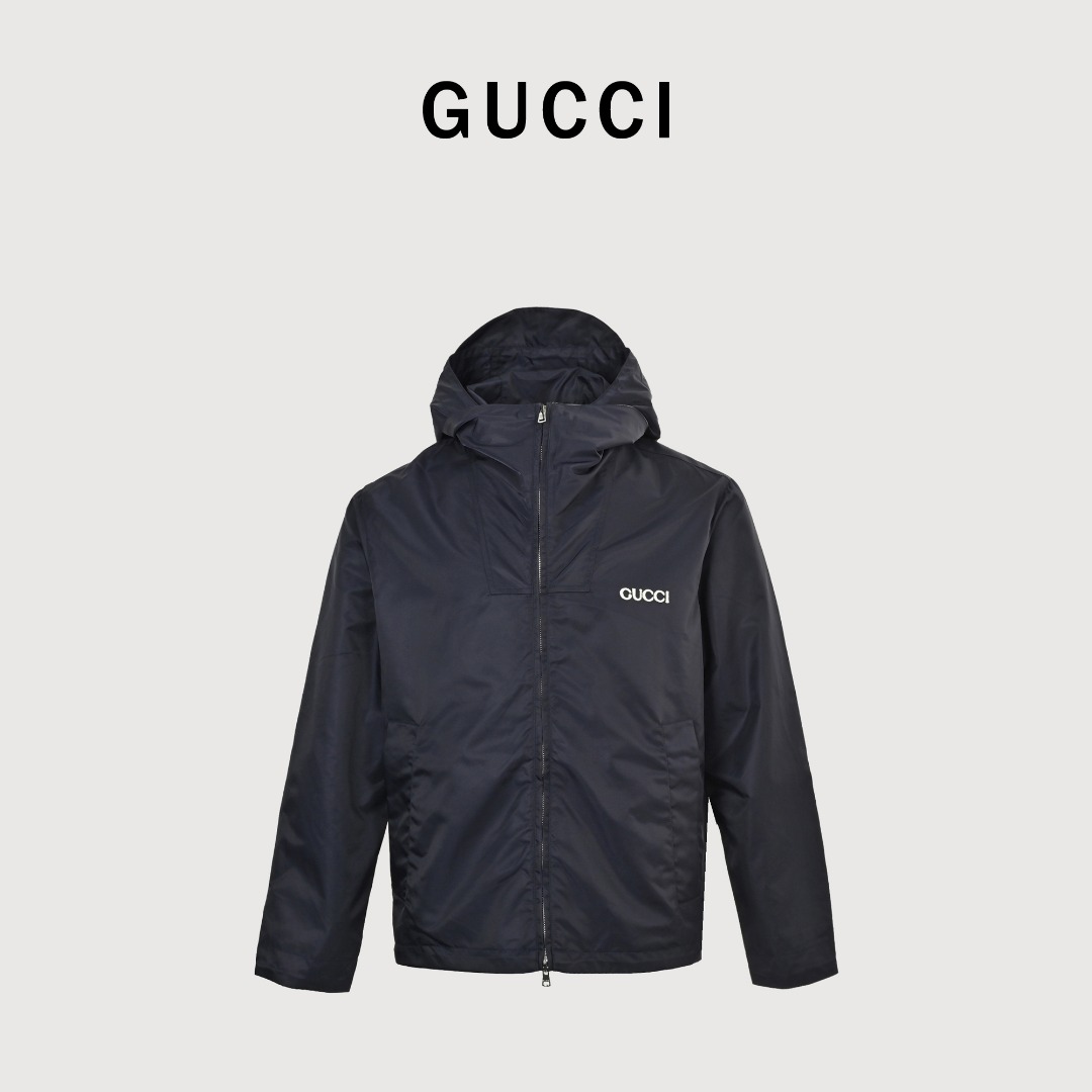 GUCCI古驰GUC 斜纹尼龙防风领连帽外套 选用100%锦纶纤维紧密编织而成的蓝色密织斜纹尼龙面料.经纬纱线之间的空隙非常小,表面呈现清晰的45度角斜向纹理.锦纶突出的耐磨性,抗拉扯等优点使成衣增加使用寿命.较小的密度强化防风性,同时兼具一定的防水性能,在室外能更好的发挥其功能性. LOGO刺绣贴饰采用0.3毫米超细聚酯绣线,经激光切割定型工艺打造浮雕质感.每片贴饰经过5道抗皱处理,确保水洗后仍保持原有形态. False Two-Piece设计增添层次感和独特性,采用高端隐形暗扣将帽子部分和大身链接一体,独立完整的双层结构,单穿叠穿皆宜.定制辅料