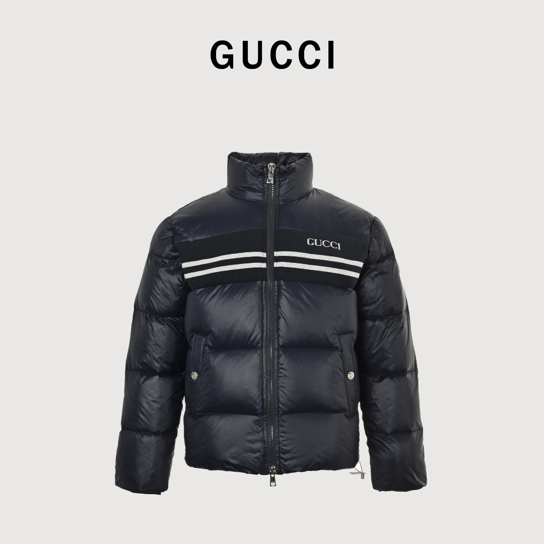 𝐆𝐮𝐜𝐜𝐢 立领条纹羽绒服
本地自取💰𝟔𝟔𝟎
古驰 胸前logo条纹 男女同款羽绒服

𝐒𝐢𝐳𝐞:𝟒𝟐 𝟒𝟒 𝟒𝟔 𝟒𝟖 𝟓𝟎
	•	版型：属于短款立领羽绒服，版型较为宽松，能够营造出休闲且具时尚感的穿搭风格，对身材的包容性较好，适合多种身形的人群驾驭。

	•	色彩：主体采用深蓝色，这种颜色沉稳大气，同时带有一定的光泽感，提升了整体的高级感；中间的黑色织带搭配白色条纹，形成经典的撞色设计，增强了视觉层次感。

材质分析

	•	面料采用高光泽的尼龙材质，这种材质具有良好的防水、防风性能，同时质感挺括，能让羽绒服保持饱满的廓形，且易于清洁和打理。

	•	填充物应为高品质鸭绒或鹅绒，从蓬松度来看，保暖性能优异，能够在寒冷的季节为穿着者提供充足的温暖。

设计细节

	•	品牌标识：正面醒目的“GU**i”白色字母刺绣，以及袖子上的品牌标志性双G元素圆形徽章，强化了品牌辨识度，是品牌身份的直观体现。

	•	拼接设计：胸前的黑色织带与白色条纹拼接，打破了纯色面料的单调感，同时织带的材质与羽绒面料形成对比，增加了设计的丰富度。

	•	功能性设计：立领设计可有效阻挡寒风；双向拉链方便穿脱和调节保暖度；两侧的口袋带有金属扣装饰，既具有实用性，又提升了细节处的精致感。