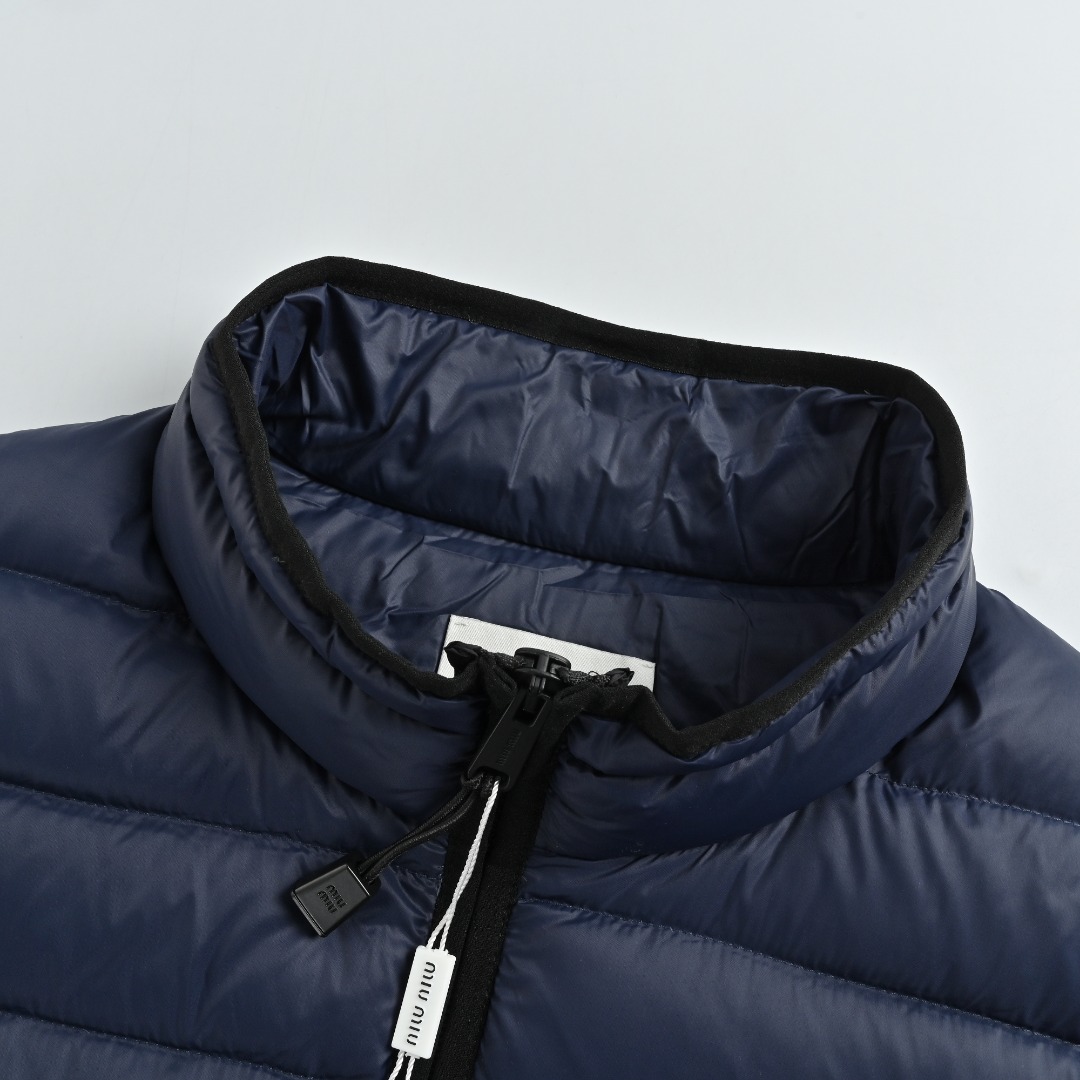 本地自取💰380 MIU MIU缪缪MM 字母绣排骨羽绒马甲 选用高支数的聚酰胺纤维打造的高端尼龙面料,以出色的抗拉强度和耐磨性能著称,其良好柔韧性使面料不易起皱,长久保持挺括有型。紧密的织法有效阻挡冷风侵袭,锁住羽绒层产生的暖空气。高密度尼龙表面形成一定的荷叶效应,小水滴不易渗透,保持内部干爽,有效提升羽绒使用寿命。 采用90国标高品质羽绒,充绒量达到了140克,蓬松度高、保暖性强,轻盈无负担,轻松应对寒冷天气。 徽标采用进口机刺绣工艺,使用先进的计算机控制系统和精密的机械部件,实现mimiu刺绣作业,精度高、线条流畅且细腻。 Size:46 48 50 52