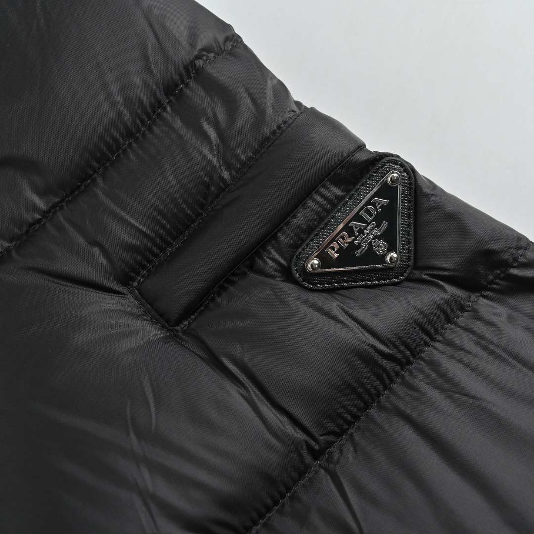 本地自取 💰650
Prada/普拉达 25Fw手臂三角标口袋立领羽绒服
采用新国标90白鸭绒填充，顶级版本，区分市面通货，男女同款全新美学灵感趣味设计,渠道性质精品。让整体造型设计更加优雅时尚，今夏最火系列，无数明星潮人追捧。裁剪工艺细节处理工整为玩味时尚增添色彩!工整细致，合身的版型构造更是独具匠心，上身不仅有着出彩的辨识度更是减龄青春。一款穿着意义还有穿搭性能都很极致的款式，绚丽的色系调配，此款的工艺必然也是极致非凡，上身的舒适度绝对足够的强大，也是奢品本质的一种彰显！柔软轻薄，触感更是极端撩人，透气性能十分之强大，尤为适合春夏季节的穿搭所需，妥妥的穿着享受，并且各处的细节以及织带的工艺都是尽善尽美，更显高级感！ 
颜色：黑色、藏青
编码：8026
尺码：48-56