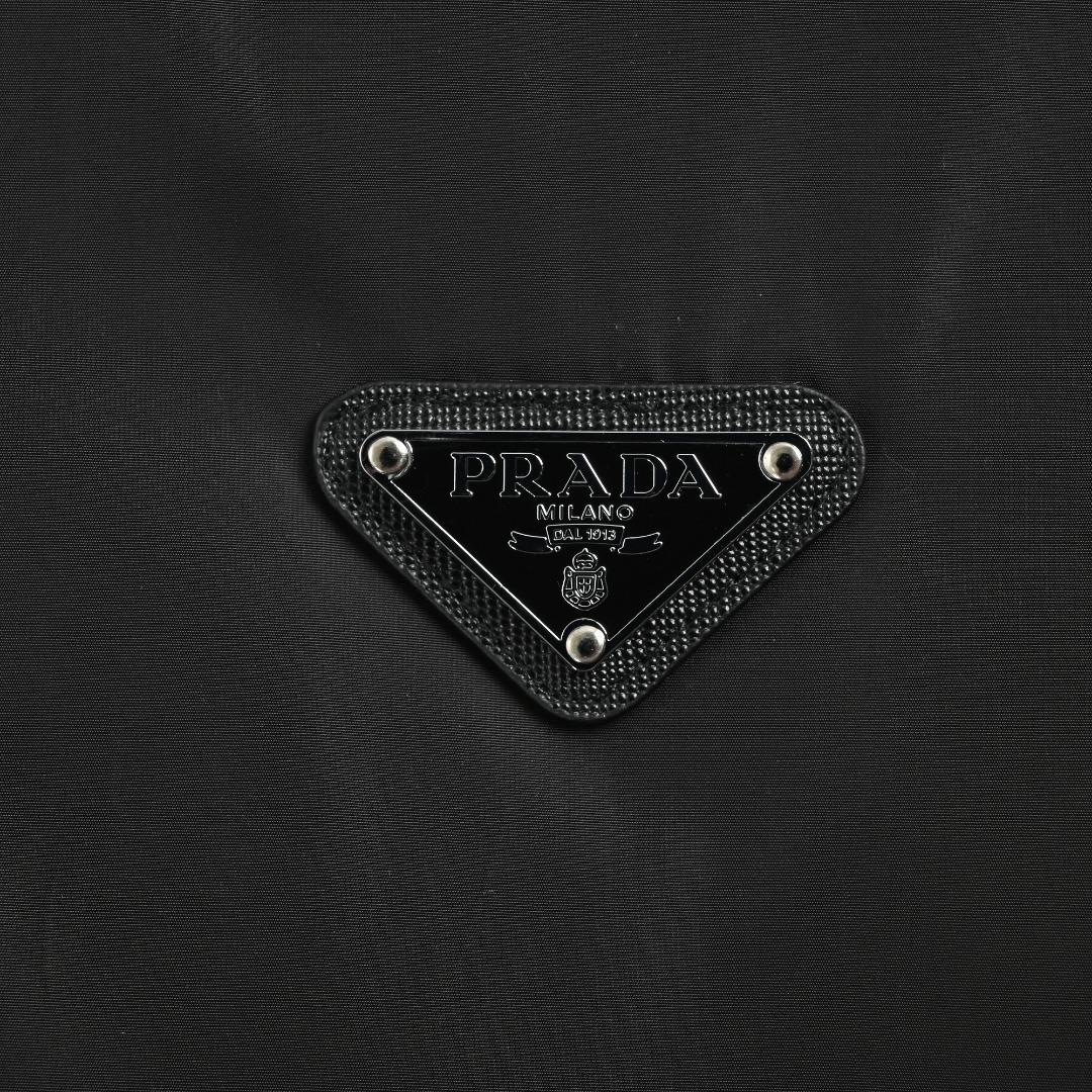 本地自取 💰600 
Prada/普拉达 25Fw下摆双边翻盖口袋薄绒外套
采用新国标90白鸭绒填充，顶级版本，区分市面通货，领口采用门扣设计，可调节，男女同款全新美学灵感趣味设计,渠道性质精品。让整体造型设计更加优雅时尚，今夏最火系列，无数明星潮人追捧。裁剪工艺细节处理工整为玩味时尚增添色彩!工整细致，合身的版型构造更是独具匠心，上身不仅有着出彩的辨识度更是减龄青春。一款穿着意义还有穿搭性能都很极致的款式，绚丽的色系调配，此款的工艺必然也是极致非凡，上身的舒适度绝对足够的强大，也是奢品本质的一种彰显！柔软轻薄，触感更是极端撩人，透气性能十分之强大，尤为适合春夏季节的穿搭所需，妥妥的穿着享受，并且各处的细节以及织带的工艺都是尽善尽美，更显高级感！ 
颜色：黑色
编码：8032
尺码：48-56