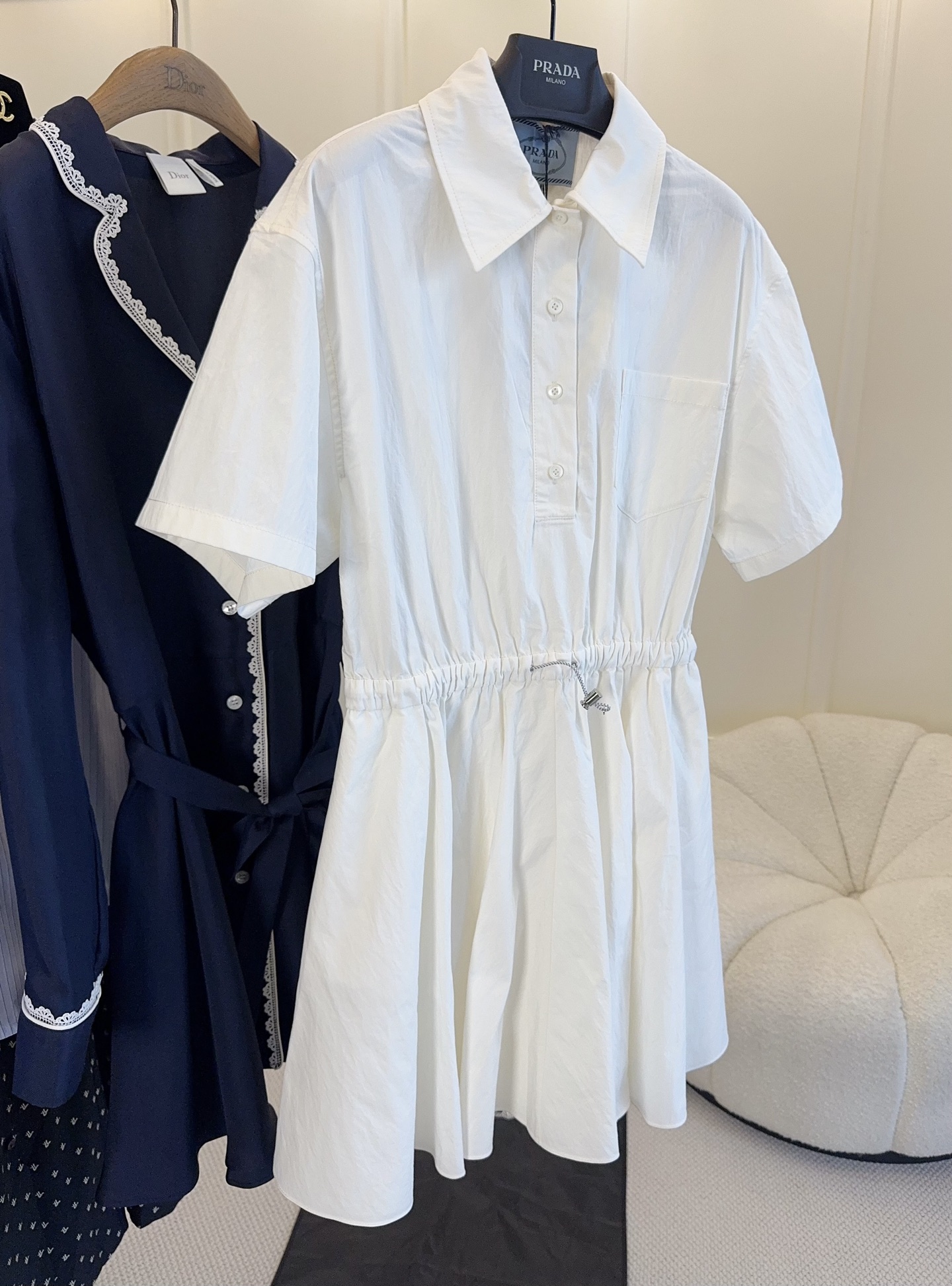 NO:830202,Prada 2026 new off-white shirt dress, light and breathable, super comfortable to wear in summer!  Classic shirt collar + short sleeve design, adjustable waist drawstring, easily modify the body proportions. A-line pleated skirt, elegant and smart, can be easily controlled for commuting, dating, and vacation. The overall is simple and elegant, white and versatile, it goes well with accessories or shoes, it is a must-have item in the summer wardrobe!  ,,prada,skirts,shirts,T-shirt,19860909Prada2026新款米白色衬衫连衣裙,轻盈透气,夏天穿超舒服！经典衬衫领+短袖设计,腰部抽绳可调节,轻松修饰身材比例.A字百褶裙摆,优雅又灵动,通勤、约会、度假都能轻松驾驭.整体简约大方,白色百搭,随手搭配配饰或鞋履都很出彩,是夏季衣橱必备单品！,,prada,skirts,shirts,T-shirt,,Women's clothing