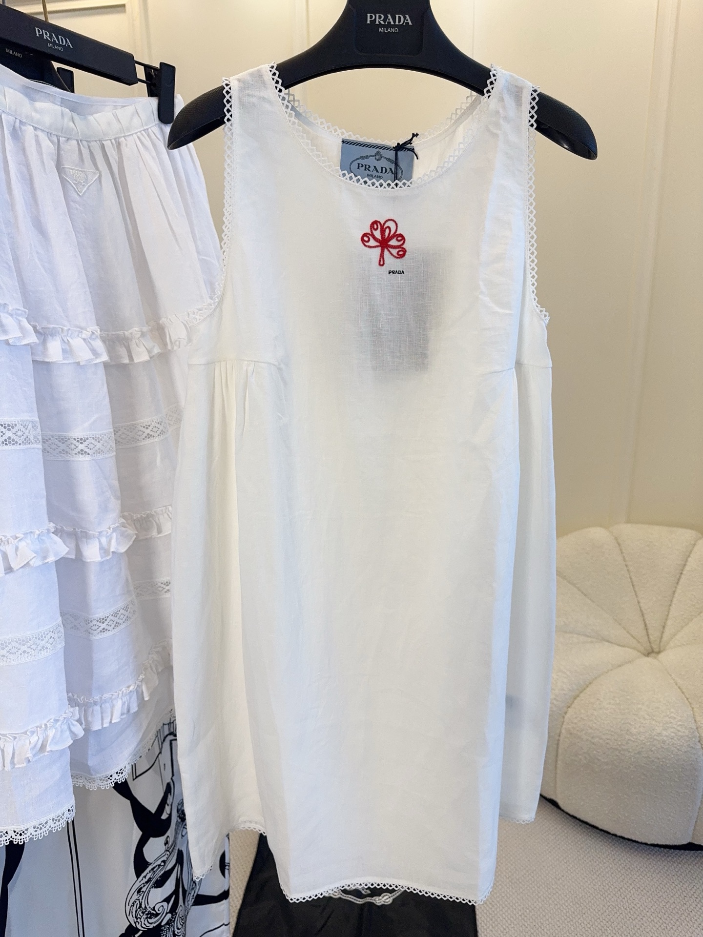 NO:838377,Prada 2026 new white textured dress, imported fabrics from Japan, breathable fabrics, loose A-line version, sleeveless design, perfect for spring and summer wear!  The red embroidery on the chest is super recognizable, with perfect details. The exquisite hollow embroidery on the skirt and neckline is retro and elegant. It can be easily used for daily outings, vacations, and exhibitions. It is casual and exquisite, and you can easily get a sense of relaxation in summer!  It looks great with short boots or sandals.,,prada,sandals,boots,skirts,19860909Prada2026新款白色肌理感连衣裙,日本进口面料,透气面料,宽松A字版型,无袖设计超适合春夏穿搭！胸前红色刺绣超有辨识度,细节满分.裙摆和领口的精致镂空刺绣,复古又优雅,日常出街、度假、逛展都能轻松驾驭,随性又精致,夏日松弛感轻松get！搭配短靴或凉鞋都很出彩哦.,,prada,sandals,boots,skirts,,Women's clothing