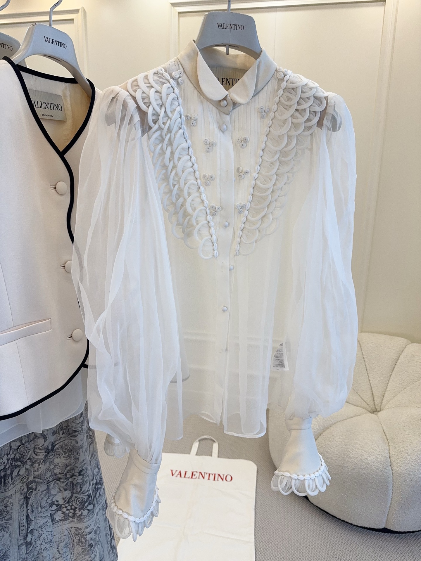 NO:846292,Valentino 2026 new white organza shirt, light and breathable, with three-dimensional plate embroidery + detachable flower collar, full of layers. Lantern sleeve design, retro and elegant, paired with a red skirt, the red and white contrasting colors are super eye-catching!  Designed by Alessandro Michele, the poetic and introspective style is suitable for formal occasions such as dinner parties and art exhibitions, and can easily show your noble temperament.,,valentino,skirts,shirts,19860909Valentino 2026新款白色欧根纱衬衫,轻盈透气,立体盘花刺绣+可拆卸花朵领口,层次感满满.灯笼袖设计,复古优雅,搭配红色半裙,红白撞色超吸睛！Alessandro Michele操刀,诗意内省风格,适合晚宴、艺术展等正式场合,轻松展现高贵气质.,,valentino,skirts,shirts,,Women's clothing