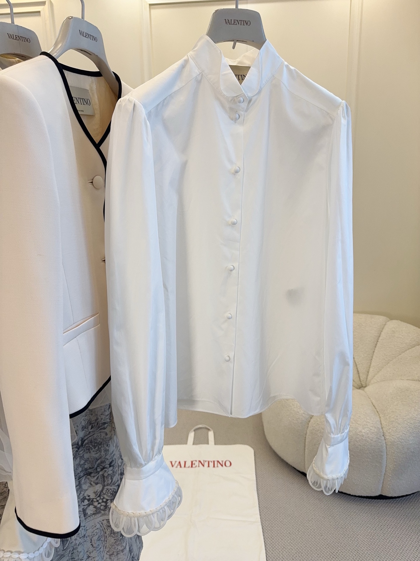 NO:859027,Valentino's 2026 new French petal sleeve white shirt is made of pure cotton, soft and breathable, with a fungus-edged stand-up collar and cuff lace design, retro and elegant, full of palace style. The long-sleeved slim cut can be easily used for commuting, dating, and daily life. Cloth-covered buttons are embellished with details, which adds a sense of sophistication!  Pair it with jeans or a skirt to easily switch between gentle and artistic or smart commuting style. It is a must-have and versatile item in your wardrobe.,,valentino,skirts,jeans,shirts,19860909Valentino2026新款法式花瓣袖白衬衫,采用纯棉材质,柔软透气,木耳边立领+袖口花边设计,复古优雅,宫廷风满满.长袖修身剪裁,通勤、约会、日常都能轻松驾驭.布包扣点缀细节,精致感UP！搭配牛仔裤或半身裙,轻松切换温柔文艺or干练通勤风,是衣橱必备百搭单品.,,valentino,skirts,jeans,shirts,,Women's clothing