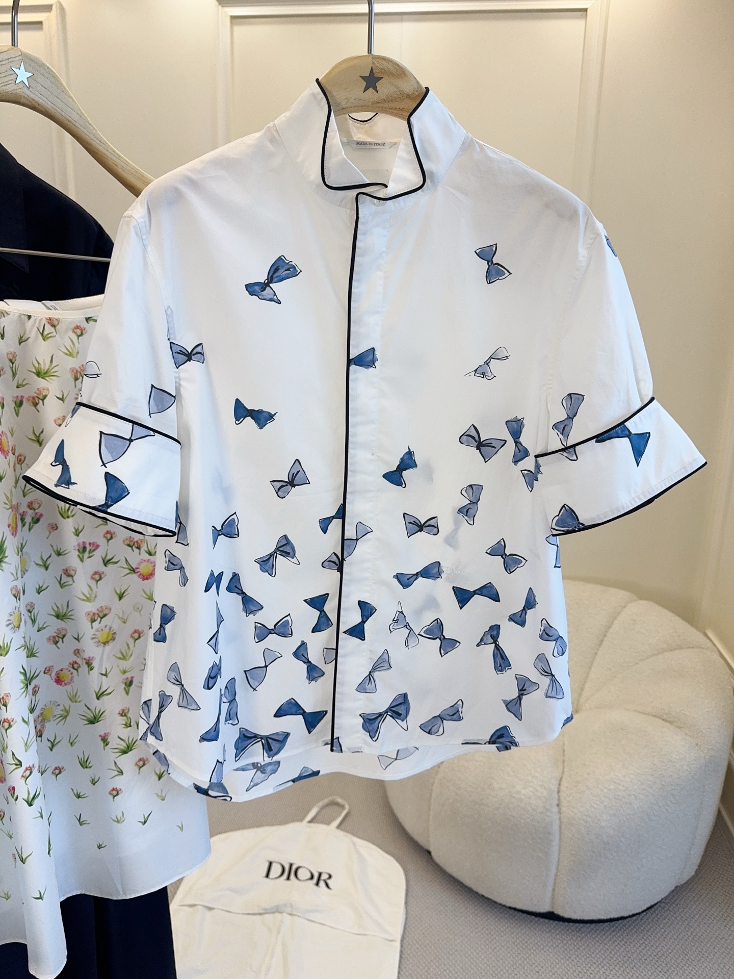NO:867411,Dior 2026 new blue bow print short-sleeved shirt, white base fabric with blue bow print, fresh and elegant, with a spring and summer atmosphere. Lightweight cotton fabric, comfortable and breathable to wear, black piping details enhance the sense of hierarchy. Short sleeves + stand-up collar design, can be easily worn in daily life or vacation, looks great with skirts or casual pants, feminine and fashionable!  ,,dior,skirts,shirts,T-shirt,19860909Dior 2026新款蓝色蝴蝶结印花短袖衬衫,白色底布配蓝色蝴蝶结印花,清新优雅超有春夏氛围感.轻薄棉质面料,穿着舒适透气,黑色滚边细节提升层次感.短袖+立领设计,日常或度假都能轻松驾驭,搭配裙装或休闲裤都很出彩,柔美又时髦！,,dior,skirts,shirts,T-shirt,,Women's clothing
