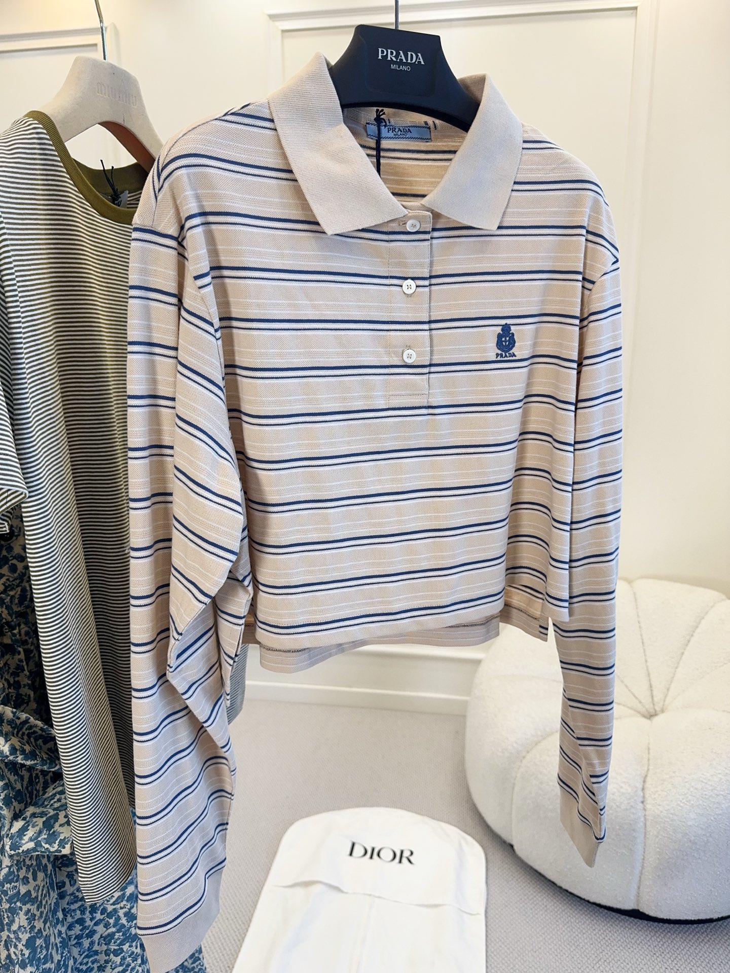 NO:884861,Prada 2026 new striped Polo shirt, apricot background with navy stripes, simple and high-end. The pique cotton material is breathable and comfortable, perfect for early autumn!  The short cut + dropped shoulder sleeves modify the body proportions, and the embroidered badge on the chest is very recognizable. The long-sleeved design is OK to wear alone or layered with a jacket. It can be easily worn for commuting, going out, and leisure. You can switch between college style or retro style at will!  ,,prada,jackets & coats,19860909Prada2026新款条Polo衫,奶杏底色配藏青条纹,简约又高级.珠地棉材质透气舒适,早秋穿超合适！短款剪裁+落肩袖,修饰身材比例,胸口刺绣徽章超有辨识度.长袖设计,单穿或叠搭外套都很OK,通勤、出街、休闲都能轻松驾驭,学院风or复古风随心切换！,,prada,jackets & coats,,Women's clothing