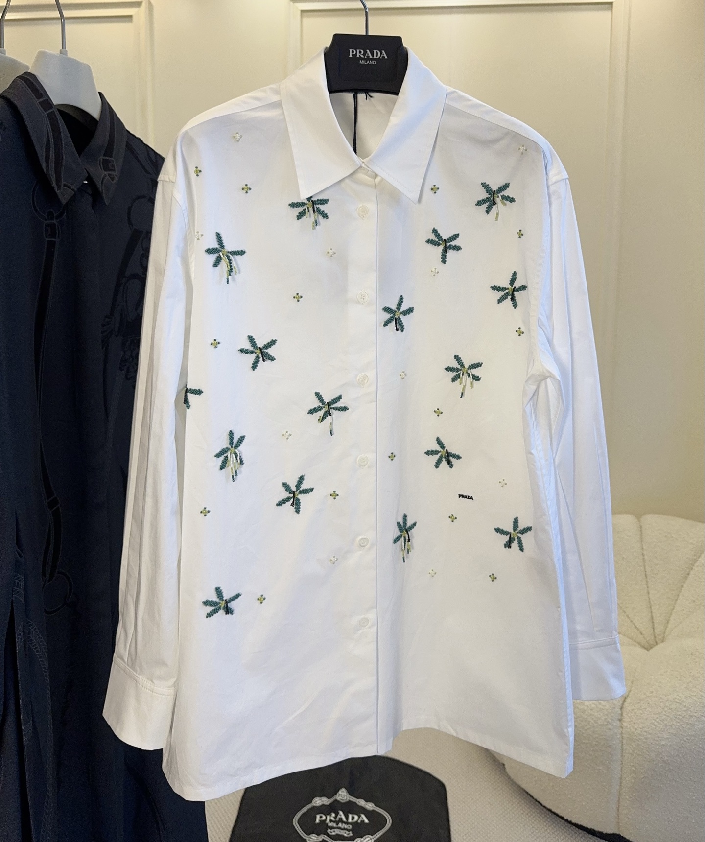 NO:901128,Prada 2026 new embroidered poplin long-sleeved shirt is made of high-quality poplin, light and breathable, super comfortable to wear in spring and summer!  The white base with green plant embroidery is full of details and full of handwork. The classic lapel + long sleeve design is easy to manage for commuting and leisure. Pair it with light-colored trousers or skirts for a fresh and natural style!  The embroidery craftsmanship is super exquisite and it is a must-have item in the spring and summer wardrobe., prada, skirts, shirts,19860909Prada 2026新款刺绣府绸长袖衬衫,采用高品质府绸,轻薄透气,春夏穿超舒服！白色底配绿色植物刺绣,细节满满,手工感十足.经典翻领+长袖设计,通勤休闲都能轻松驾驭,搭配浅色裤装或裙装,清新自然风格get！刺绣工艺超精致,是春夏衣橱必备亮点单品.,,prada,skirts,shirts,,Women's clothing