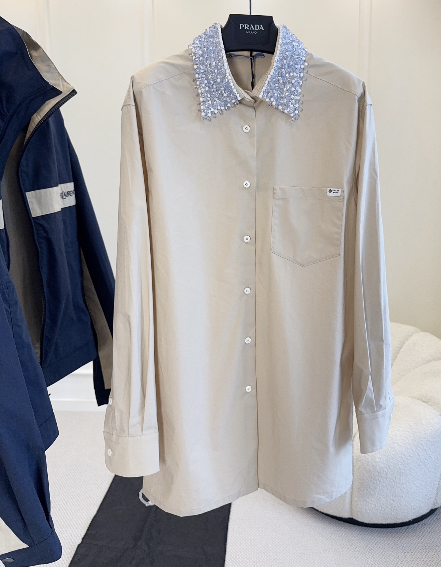 NO:946104,Prada 2026 autumn and winter series crystal collar shirt, light khaki cotton fabric, light and breathable, super comfortable to wear in spring and summer!  The neckline is hand-beaded, exquisite and layered, and the details are perfect. The cut is simple and elegant, and the cuffs and chest pockets are very practical. It can be easily worn in daily or formal occasions. Pair it with a skirt or jeans, it is elegant and fashionable, and you can easily get a high-end look!  ,,prada,skirts,jeans,shirts,19860909Prada 2026秋冬系列水晶领衬衫,浅卡其棉质面料,轻盈透气,春夏穿超舒服！领口手工钉珠,精致又有层次感,细节满分.剪裁简约大方,袖口和胸前口袋都很实用,日常或正式场合都能轻松驾驭.搭配半裙或牛仔裤,优雅又时髦,轻松get高级感穿搭！,,prada,skirts,jeans,shirts,,Women's clothing