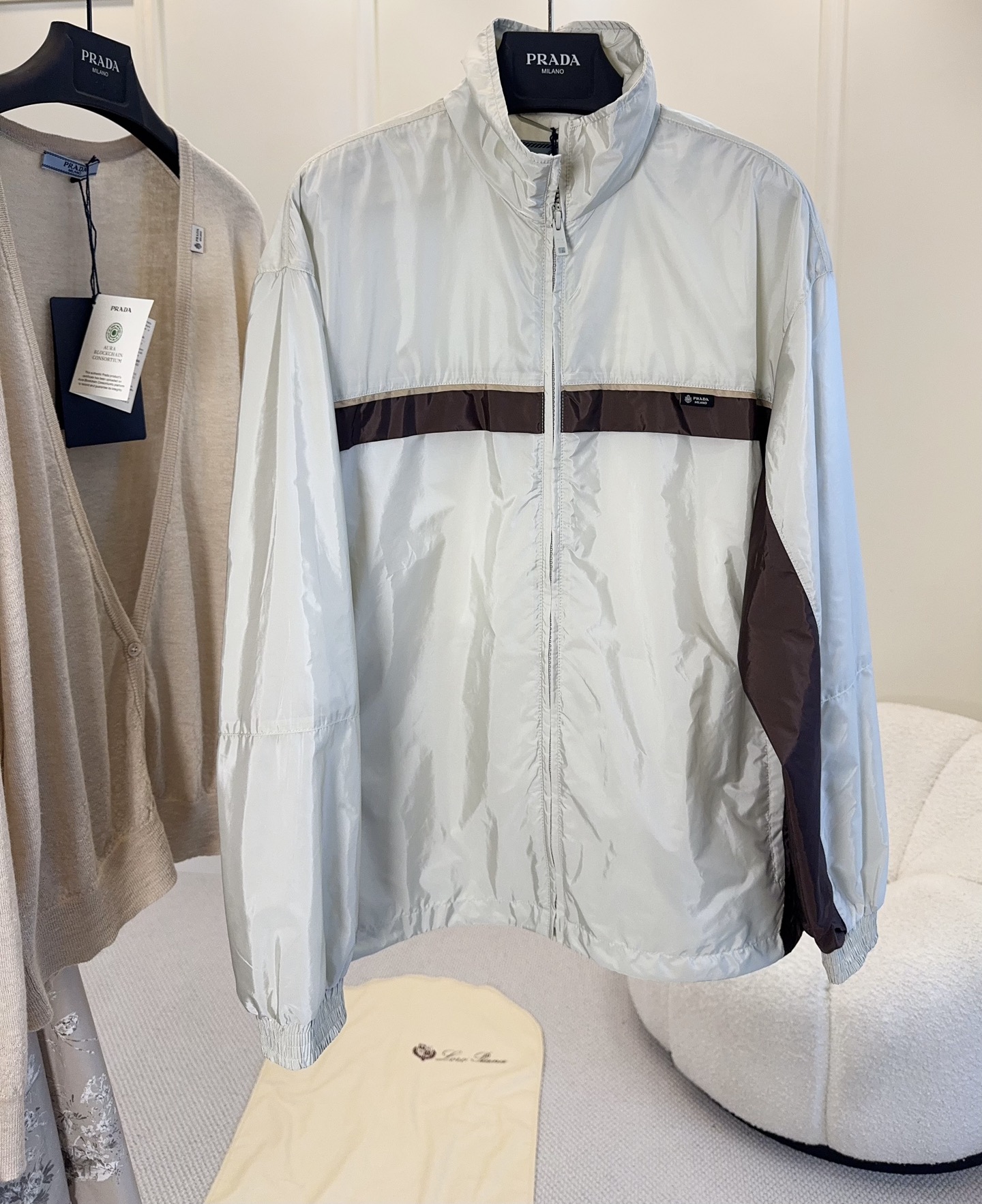 NO:953653,PRADA's 2026 new retro color-blocking jacket is a reimagining of the 90s retro sports style, bringing the brand's iconic minimalist sense of luxury. The off-white base is paired with dark brown contrasting strips, and the contrasting color dividing lines are neat and smooth, with a retro and relaxed atmosphere; the stand-up collar is fully zippered, elasticated cuffs are windproof and temperature-locking, and the lightweight anti-wrinkle functional fabric is both breathable and windproof.  Usability. The side seams of the body and the small woven label on the chest hide the brand logo, without stacking exaggerated logos, which perfectly interprets Prada's low-key and restrained luxury aesthetics. The loose off-shoulder version is the same for men and women, and can be worn alone for refreshing commuting. Layer it with a sweater to create a layered look. It is versatile in all seasons and is not picky. The brand's collection-level retro sports jacket.,, prada, jackets  & coats,jackets & coats,sweaters,19860909PRADA2026新款复古拼色夹克,90年代复古运动风重塑,把品牌标志性极简高级感拉满.米白基底搭配深棕撞色条带,撞色分割线条利落流畅,自带复古松弛氛围感；立领全拉链开合,松紧束口袖口防风锁温,轻便抗皱机能面料,兼具透气与抗风实用性.衣身侧缝、胸前小织标暗藏品牌标识,不堆砌浮夸大logo,完美诠释Prada低调克制的奢品美学.宽松落肩版型男女同款,单穿清爽通勤,内搭毛衣打造层次穿搭,四季百搭不挑人,品牌收藏级复古运动外套.,,prada,jackets & coats,jackets & coats,sweaters,,Women's clothing
