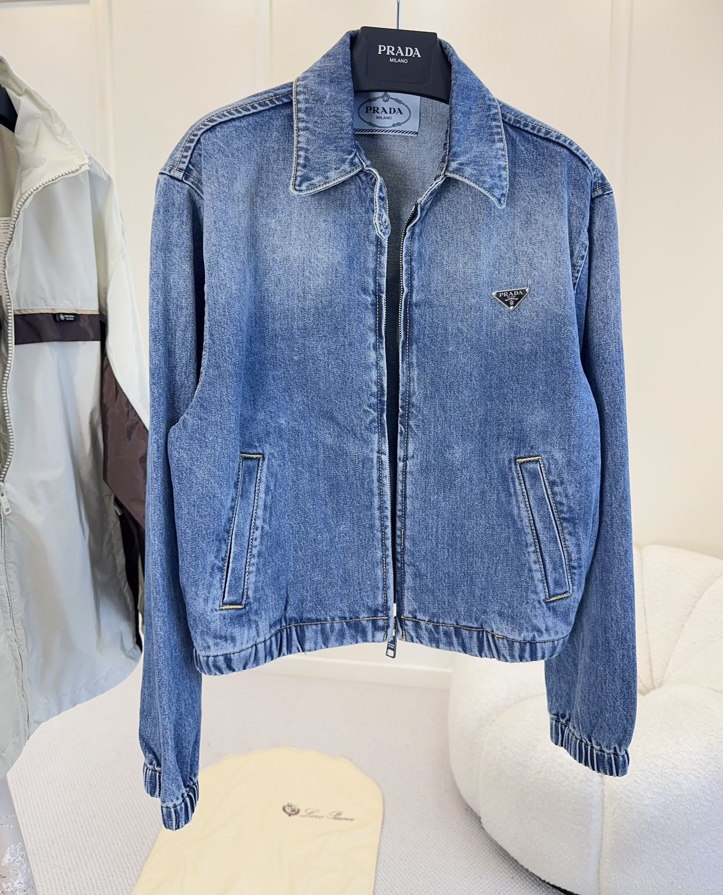 NO:953614,PRADA2026 new classic triangle logo washed denim short jacket  , an Italian retro casual benchmark item, integrating the brand's iconic minimalist luxury into denim fabrics. Heavy-duty washed distressed denim, with a gradient blue tone and built-in retro filter. It is stiff and stylish and not easy to collapse; the lapel zipper design is neat and capable, and the hem and cuffs  Elasticized cuffs optimize body proportions. The metal triangle logo on the chest is the brand's core recognition symbol, with no unnecessary exaggerated printing, perfectly implementing Prada's low-key and high-end design language; the diagonal pockets are practical and stylish, and the topstitching stitching enhances the workwear texture.  The short high-waisted cut is the same for men and women, and can easily create a 37-point figure. It is suitable for matching with wide-leg pants, skirts, and straight trousers. It can be used for daily commuting, street wear, and light casual occasions. It is a classic collection of the brand wardrobe.,, prada, skirts, jackets & coats,19860909PRADA2026新款经典三角标水洗牛仔短夹克 ,意式复古休闲标杆单品,把品牌标志性极简奢感融入丹宁面料.重工水洗做旧牛仔布,深浅渐变蓝调自带复古滤镜,硬挺有型不易软塌；翻领拉链开襟设计,利落干练,下摆与袖口松紧收口,优化身材比例.胸口金属三角徽标是品牌核心辨识度符号,无多余浮夸印花,完美贯彻Prada低调高级的设计语言；斜插口袋实用兼顾造型,明线车缝强化工装质感. 短款高腰剪裁男女同款,轻松打造三七分身材,搭配阔腿裤、半身裙、直筒西裤皆适配,日常通勤、街头穿搭、轻休闲场合全能驾驭,品牌衣橱经典典藏款.,,prada,skirts,jackets & coats,,Women's clothing