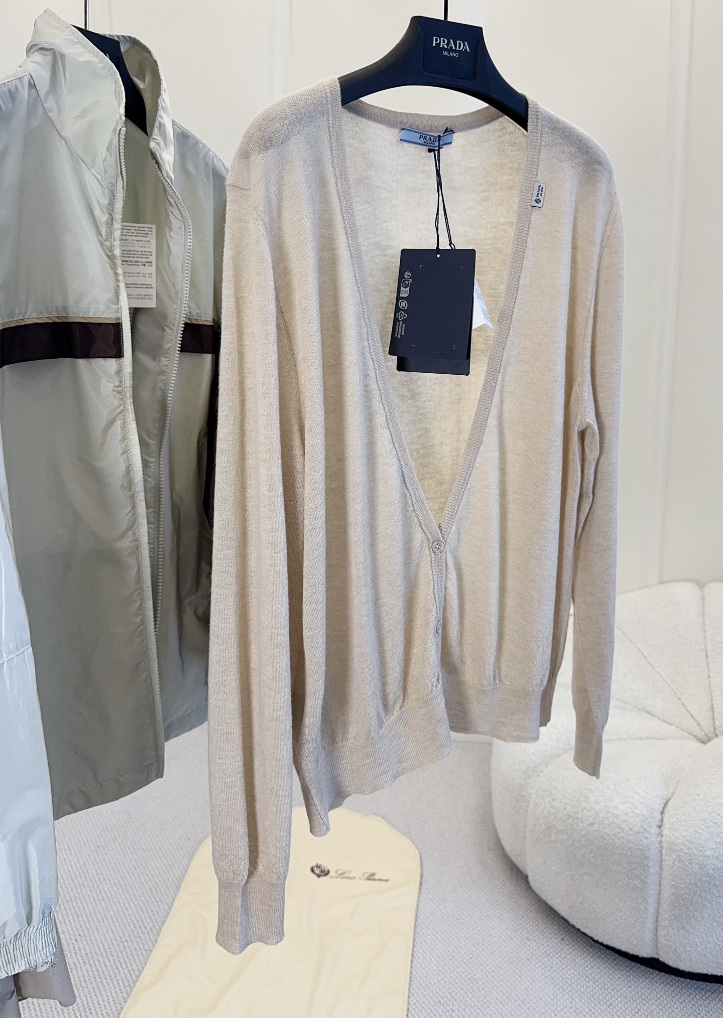 NO:953590,PRADA2026 new superfine cashmere wool V-neck oatmeal color knitted cardigan, a representative item of Italian minimalist intellectual style, integrates the brand's low-key and restrained luxury into soft knitted fabrics. The cashmere wool yarn is selected, the texture is delicate and light, soft and skin-friendly without tying, the soft oatmeal original color is low saturation and versatile, not picky yellow and white skin, suitable for all seasons. Deep V-neck single-breasted classic version, gathered rib sleeves  The mouth and hem fit the body shape without being bulky; the micro woven label on the side hides the brand logo without exaggerating the large logo, which perfectly fits the simple and advanced design core of Prada. It is gentle and intellectual when worn alone, with a shirt underneath and a high collar to create a sense of layering. It is suitable for all scenarios of commuting, dating, and light business. It is a basic collection of the brand that will never go out of style in the wardrobe.,, prada, shirts,19860909PRADA2026新款超细羊绒羊毛V领燕麦色针织开衫,意式极简知性代表单品,将品牌低调克制的奢感融入柔软针织面料.甄选羊绒羊毛纱线,肌理细腻轻盈,软糯亲肤无扎感,柔和燕麦原色低饱和百搭,不挑黄皮白皮,四季适配.深V领单排扣经典版型,收束罗纹袖口与下摆,贴合身形不臃肿；侧边微型织标暗藏品牌标识,无夸张大logo,完美契合Prada简约高级的设计内核.单穿温柔知性,内搭衬衫、高领打底打造层次感,通勤、约会、轻商务全场景适配,衣橱永不过时的品牌基础典藏款.,,prada,shirts,,Women's clothing