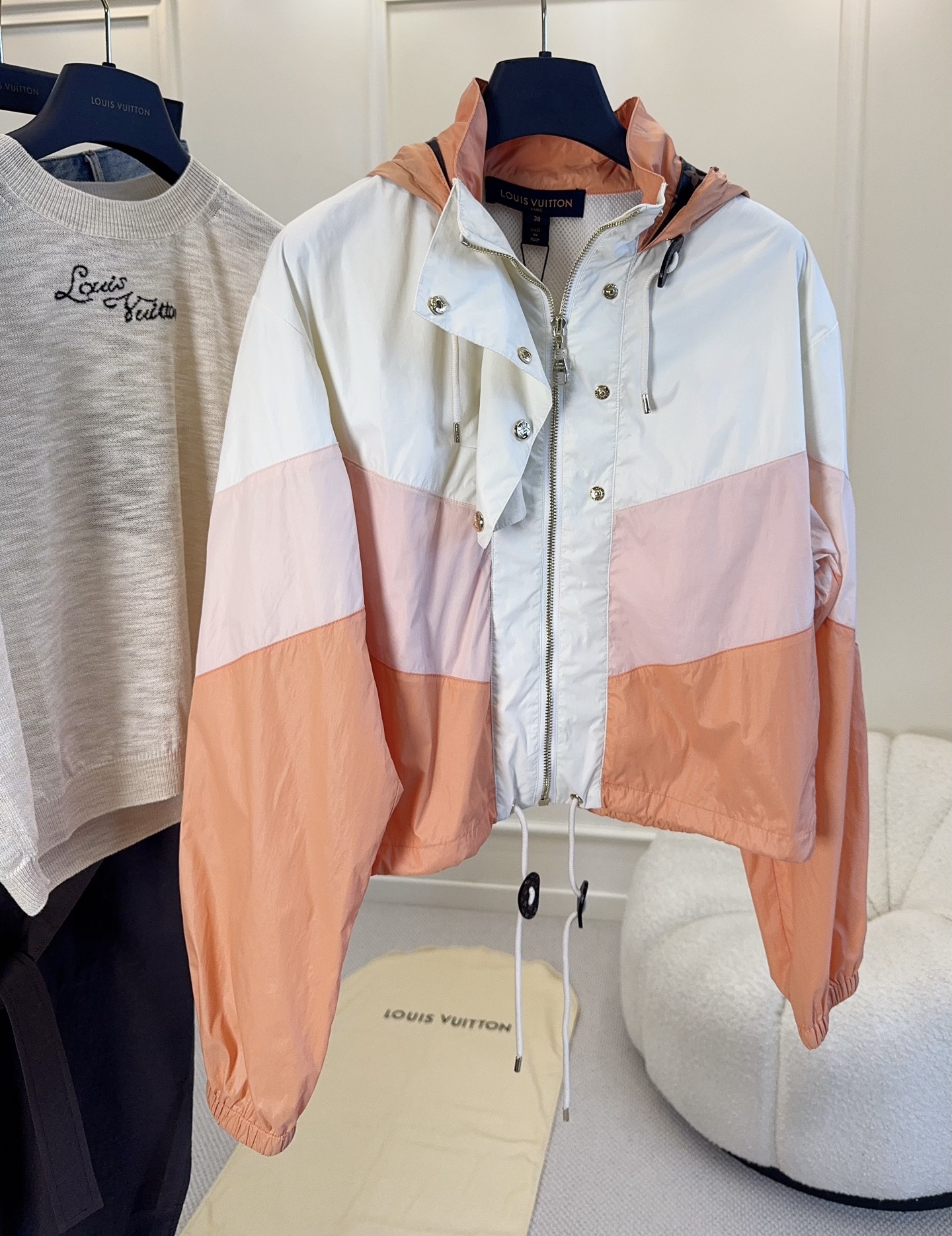 NO:954802,LV2026 new gradient color-blocked short hooded jacket with three-color splicing of vitality peach, wear it in spring and sunset!  White + light pink + warm orange layered contrasting colors, visually soft and white. The short cut raises the waistline, easily optimizing the body proportions. The dual design of half-open zipper + metal buttons makes it easy to put on and take off. It comes with a branded dark pattern drawstring hood and elastic cuffs, which is windproof and practical. The light and breathable windproof fabric is suitable for sun protection when traveling and daily commuting. Casual, light and luxurious, but also energetic, it can be worn alone or layered, and it has a girlish feel.,, louis  vuitton,hats,19860909LV2026新款渐变拼色短款连帽冲锋衣 元气蜜桃三色拼接,把春日落日穿在身上！ 白+浅粉+暖橘层次撞色,视觉柔和又显白. 短款剪裁拉高腰线,轻松优化身材比例. 半开拉链+金属排扣双重设计,穿脱灵活. 自带品牌暗纹抽绳连帽,袖口松紧收口,防风实用. 轻薄透气的防风面料,出游防晒、日常通勤都适配. 休闲轻奢兼具活力,单穿叠搭都出彩,少女感十足.,,louis vuitton,hats,,Women's clothing