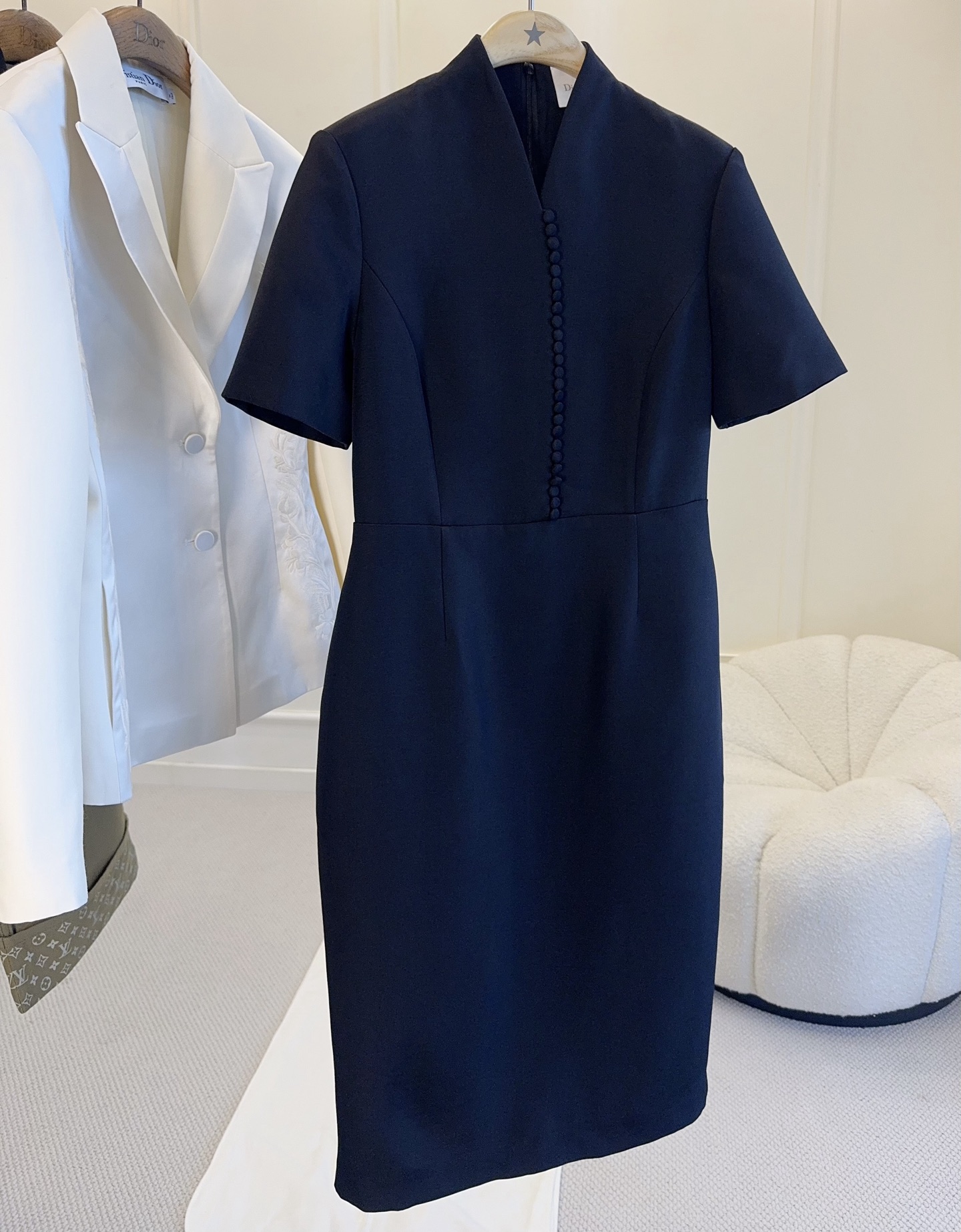 NO:956818,Dior2026 new early autumn silk wool classic black elegant straight-leg hip-hugging dress｜A timeless intellectual jersey with a neat small stand-up collar extending an elegant V-shaped opening, modifying the neck line, and bringing with it an oriental subtle beauty.  The placket has a whole row of hand-wrapped ball buttons, full of retro craftsmanship, and becomes the visual highlight of the entire skirt. The short sleeves are well-cut, the high waistline is segmented to optimize the body proportions, the three-dimensional panels precisely shape the waist and abdomen, and the straight mid-length skirt is flattering to the body shape. High-density and stiff silk wool surface  The material has a drape that is not easy to wrinkle online, and the matte black color is calm and high-end. It is suitable for commuting meetings, formal meetings, and banquets. The simple version contains exquisite details and creates a calm and elegant elite temperament.,, dior, skirts, T-shirt,19860909Dior2026早秋新款丝毛经典黑优雅直筒包臀连衣裙｜永不过时的知性战袍利落小立领延伸出雅致V型开口,修饰脖颈线条,自带东方含蓄美感. 门襟一整排手工包布圆珠扣,复古工艺感满满,成为整条裙子的视觉亮点.短袖剪裁得体大方,高腰线分割优化身材比例,立体裁片精准收塑腰腹,直筒中长裙摆包容身形.高密挺括丝毛面料,垂感在线不易起皱,哑光黑色沉稳高级.通勤会议、正式会晤、宴会场合都适配,简约版型蕴藏考究细节,穿出从容大气的精英气质.,,dior,skirts,T-shirt,,Women's clothing