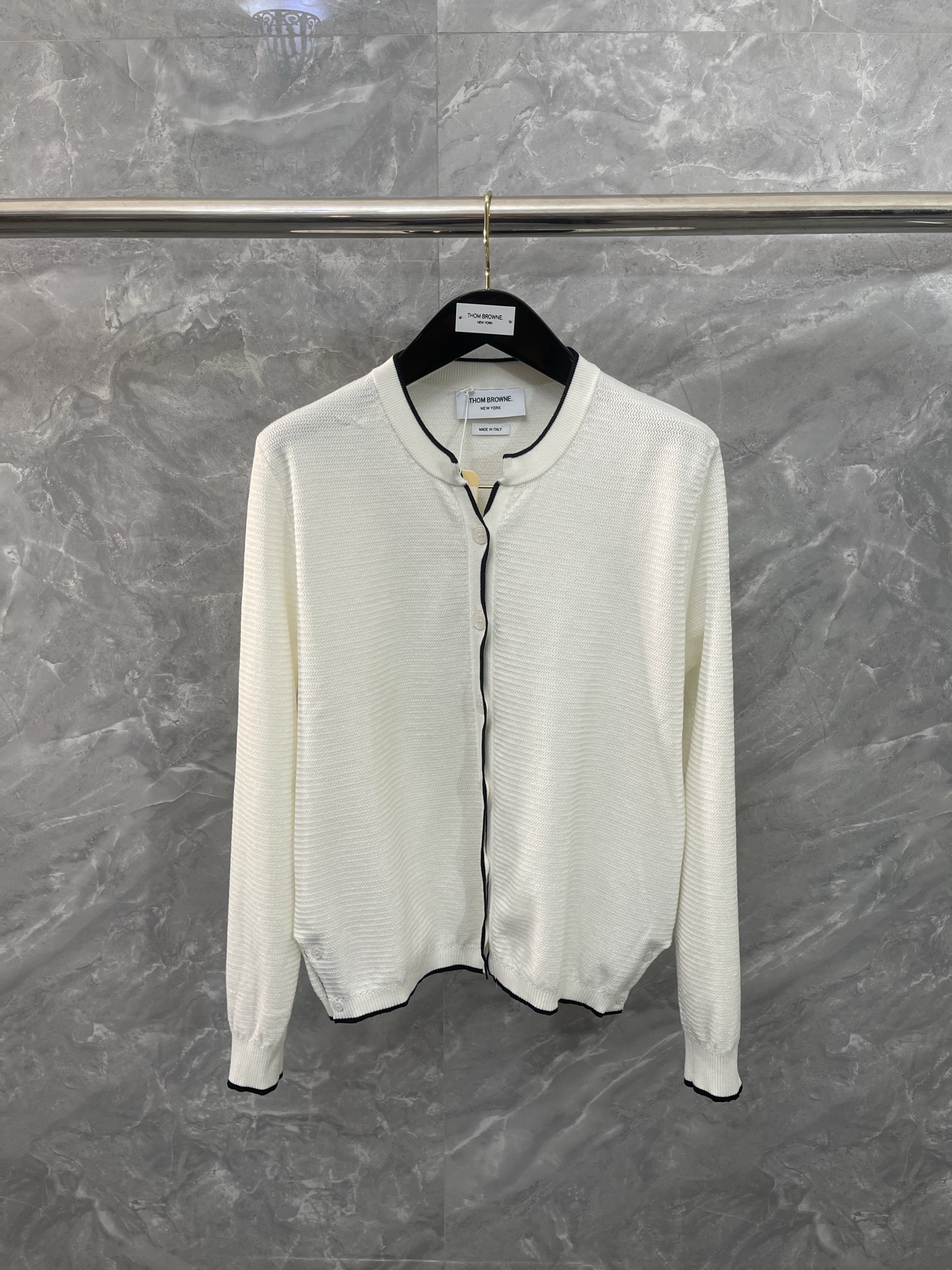 NO:637895,TB#MINIMALISTism#The classic knitted cardigan uses extremely simple lines to outline an undeniable high-end aura. The iconic black piping accurately outlines the collar, placket and cuffs, which is in sharp contrast with the pure white body, continuing the brand's consistent clear outline and architectural sense. Each button echoes the overall tone in a low-key manner, and the details show restrained sophistication.  It is a 'style basic', but it is far more than basic. It can be draped casually on the shoulders to add relaxation and elegance to a suit; it can also be worn on its own, paired with suit pants or skirts. size012, Thom Browne-clothing,thom browne,skirts,business suit,alexander wang19860909TB#极简主义#经典针织开衫,以极致简约的线条,勾勒出不容置喙的高级气场 标志性的黑色滚边精准勾勒领口、门襟与袖口,与纯白主体形成鲜明对比,延续品牌一贯的清晰轮廓与建筑感 每一颗纽扣都低调呼应整体色调,细节处尽显内敛的精致 它是一件“风格基础款”,却远超基础.可随意搭在肩头,为西装增添一份松弛与优雅；亦可独自成章,搭配西装裤或半裙. size012,汤姆布朗-服装,thom browne,skirts,business suit,alexander wang,Women's clothing