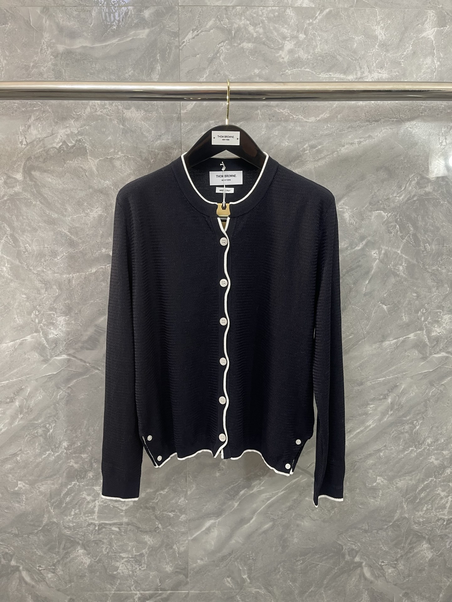 NO:637898,TB#MINIMALISTism# The classic knitted cardigan uses extremely simple lines to outline an undeniable high-end aura. The iconic white piping accurately outlines the collar, placket and cuffs, which is in sharp contrast with the pure black body, continuing the brand's consistent clear outline and architectural sense. Each button is low-key echoing the overall tone, and the details show restrained sophistication.  It is a 'style basic', but it is far more than basic. It can be draped casually on the shoulders to add relaxation and elegance to a suit; it can also be worn on its own and paired with suit pants or skirts. size012, Thom Browne-clothing,thom browne,skirts,business suit,alexander wang19860909TB#极简主义#经典针织开衫,以极致简约的线条,勾勒出不容置喙的高级气场 标志性的白色滚边精准勾勒领口、门襟与袖口,与纯黑主体形成鲜明对比,延续品牌一贯的清晰轮廓与建筑感 每一颗纽扣都低调呼应整体色调,细节处尽显内敛的精致 它是一件“风格基础款”,却远超基础.可随意搭在肩头,为西装增添一份松弛与优雅；亦可独自成章,搭配西装裤或半裙. size012,汤姆布朗-服装,thom browne,skirts,business suit,alexander wang,Women's clothing