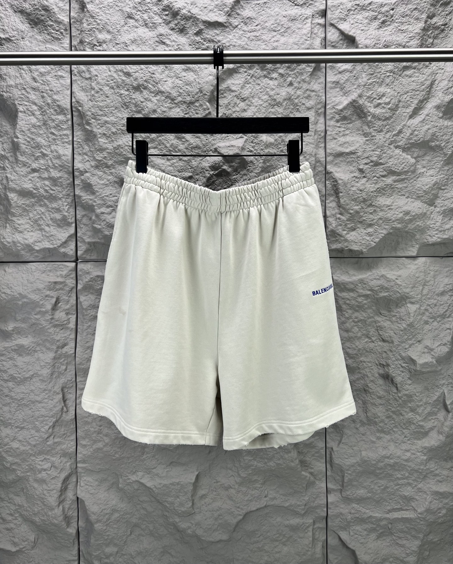 Balenciaga BALENCI*GA logo刺绣短裤这款白色休闲短裤采用重磅精梳棉混纺面料 经预缩与磨毛处理 布面呈现细腻绒感 亲肤透气且不易变形 腰头采用多道抽褶松紧带工艺 内置高弹橡筋与扁平抽绳 可自由调节松紧度 穿着无束缚感 裤身采用立体剪裁 侧缝与内缝使用双线包边工艺 牢固耐穿且避免线头外露 左裤腿处采用进口电脑刺绣工艺 精准绣制品牌字母标识 针脚细密平整 色彩饱和度高且不易脱落 裤脚采用双针卷边锁缝工艺 边缘平整挺括 视觉上更显利落 适配日常休闲 运动等多种场景 兼具实用性与潮流质感 整体走线平直细腻 面料舒适柔软 颜色一致无色差 能与同款搭配营造 造型 驾驭各种场合 定制辅料 三标齐全