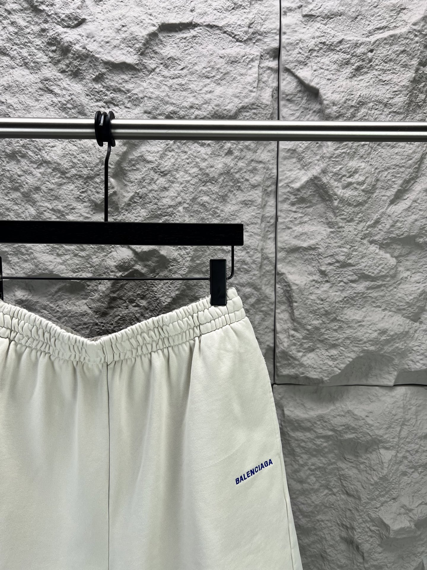 Balenciaga BALENCI*GA logo刺绣短裤这款白色休闲短裤采用重磅精梳棉混纺面料 经预缩与磨毛处理 布面呈现细腻绒感 亲肤透气且不易变形 腰头采用多道抽褶松紧带工艺 内置高弹橡筋与扁平抽绳 可自由调节松紧度 穿着无束缚感 裤身采用立体剪裁 侧缝与内缝使用双线包边工艺 牢固耐穿且避免线头外露 左裤腿处采用进口电脑刺绣工艺 精准绣制品牌字母标识 针脚细密平整 色彩饱和度高且不易脱落 裤脚采用双针卷边锁缝工艺 边缘平整挺括 视觉上更显利落 适配日常休闲 运动等多种场景 兼具实用性与潮流质感 整体走线平直细腻 面料舒适柔软 颜色一致无色差 能与同款搭配营造 造型 驾驭各种场合 定制辅料 三标齐全