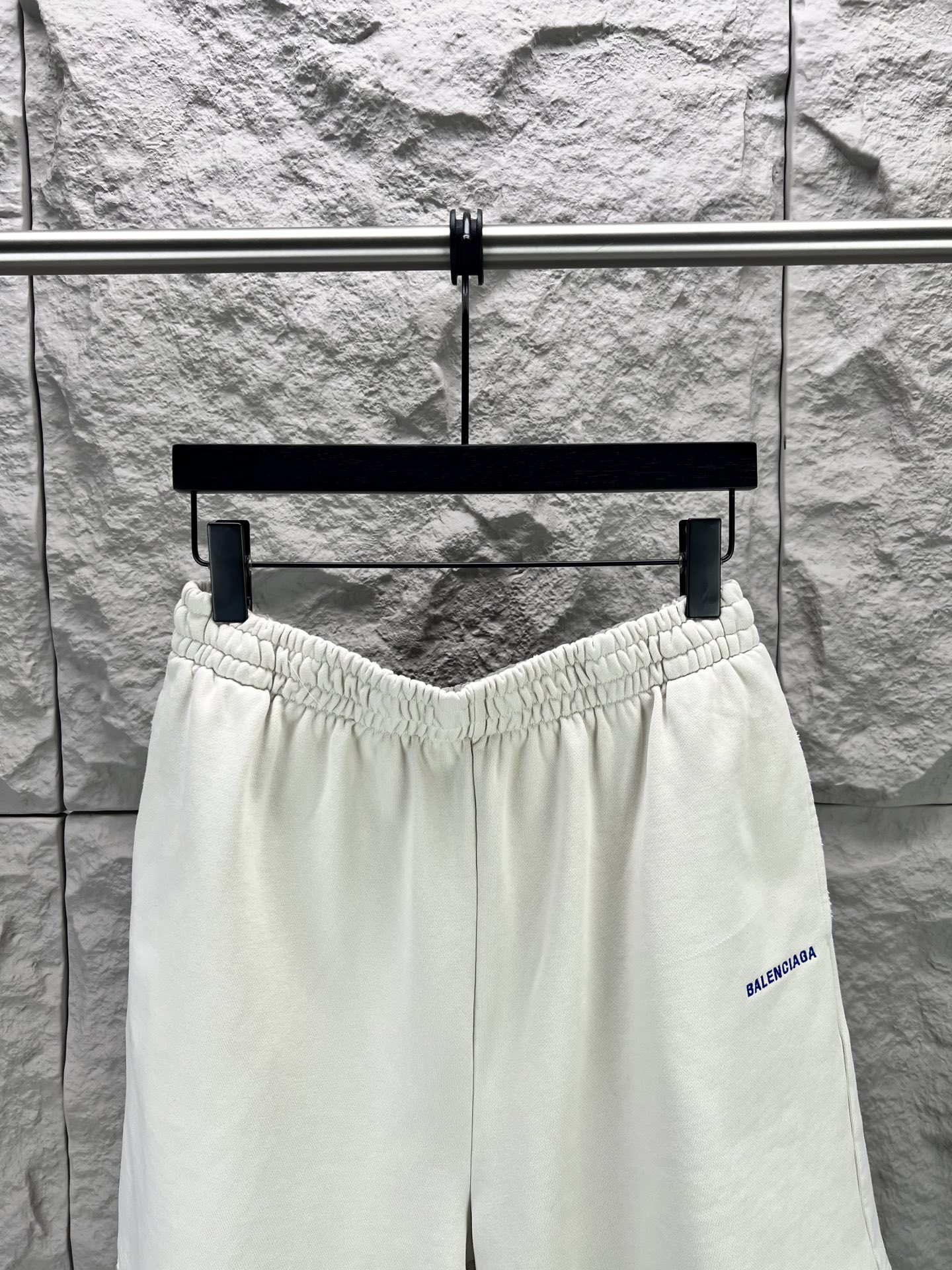 Balenciaga BALENCI*GA logo刺绣短裤这款白色休闲短裤采用重磅精梳棉混纺面料 经预缩与磨毛处理 布面呈现细腻绒感 亲肤透气且不易变形 腰头采用多道抽褶松紧带工艺 内置高弹橡筋与扁平抽绳 可自由调节松紧度 穿着无束缚感 裤身采用立体剪裁 侧缝与内缝使用双线包边工艺 牢固耐穿且避免线头外露 左裤腿处采用进口电脑刺绣工艺 精准绣制品牌字母标识 针脚细密平整 色彩饱和度高且不易脱落 裤脚采用双针卷边锁缝工艺 边缘平整挺括 视觉上更显利落 适配日常休闲 运动等多种场景 兼具实用性与潮流质感 整体走线平直细腻 面料舒适柔软 颜色一致无色差 能与同款搭配营造 造型 驾驭各种场合 定制辅料 三标齐全