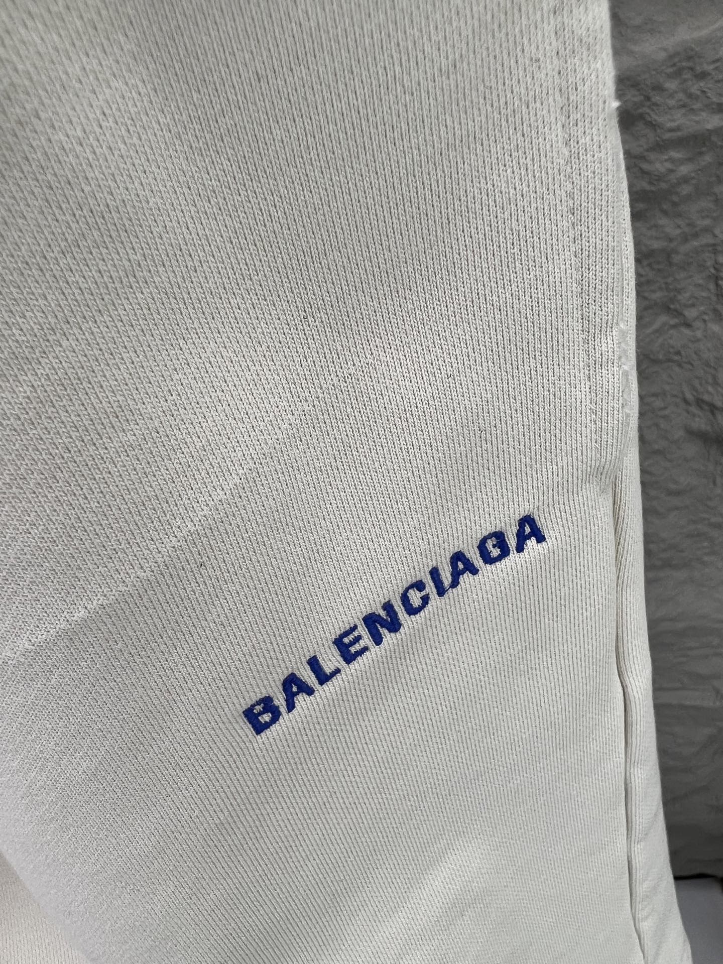 Balenciaga BALENCI*GA logo刺绣短裤这款白色休闲短裤采用重磅精梳棉混纺面料 经预缩与磨毛处理 布面呈现细腻绒感 亲肤透气且不易变形 腰头采用多道抽褶松紧带工艺 内置高弹橡筋与扁平抽绳 可自由调节松紧度 穿着无束缚感 裤身采用立体剪裁 侧缝与内缝使用双线包边工艺 牢固耐穿且避免线头外露 左裤腿处采用进口电脑刺绣工艺 精准绣制品牌字母标识 针脚细密平整 色彩饱和度高且不易脱落 裤脚采用双针卷边锁缝工艺 边缘平整挺括 视觉上更显利落 适配日常休闲 运动等多种场景 兼具实用性与潮流质感 整体走线平直细腻 面料舒适柔软 颜色一致无色差 能与同款搭配营造 造型 驾驭各种场合 定制辅料 三标齐全