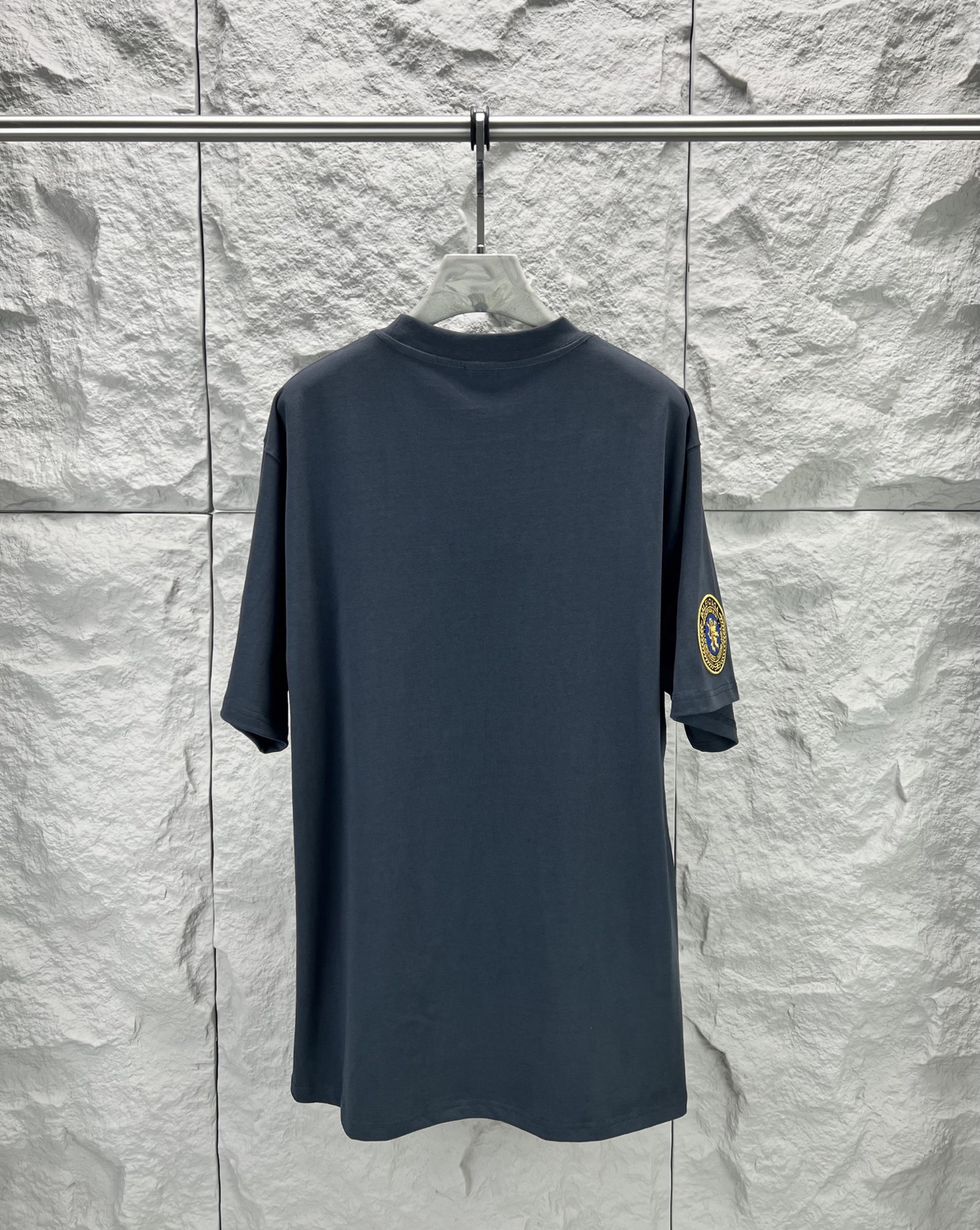 Vetements 胸前字母狮标徽章短袖280克精棉平纹面料 双纱拉架罗纹 平纹纯棉面料是一种高质量的棉纺织品 具有紧密的纺纱技术和高支数 这种面料具有柔软 舒适 透气和吸湿性好等特点 同时其纺织工艺要求也较高 纯棉质织物组织结构为平纹 面料的织物表面平整细腻 质地紧密 具有良好的吸湿透气性和舒适性 能够保持干爽舒适 由于其紧密的纺纱工艺 徽标刺绣章仔点缀 徽标采用进口定做绣线具有光泽感的丝光绣线进行定染 精细的细节处理 造就了立体微浮雕的刺绣效果 哑光挨针刺绣工艺是一种刺绣技术 颜色一致无色差 能与同款搭配营造 造型 驾驭各种场合 定制辅料 三标齐全