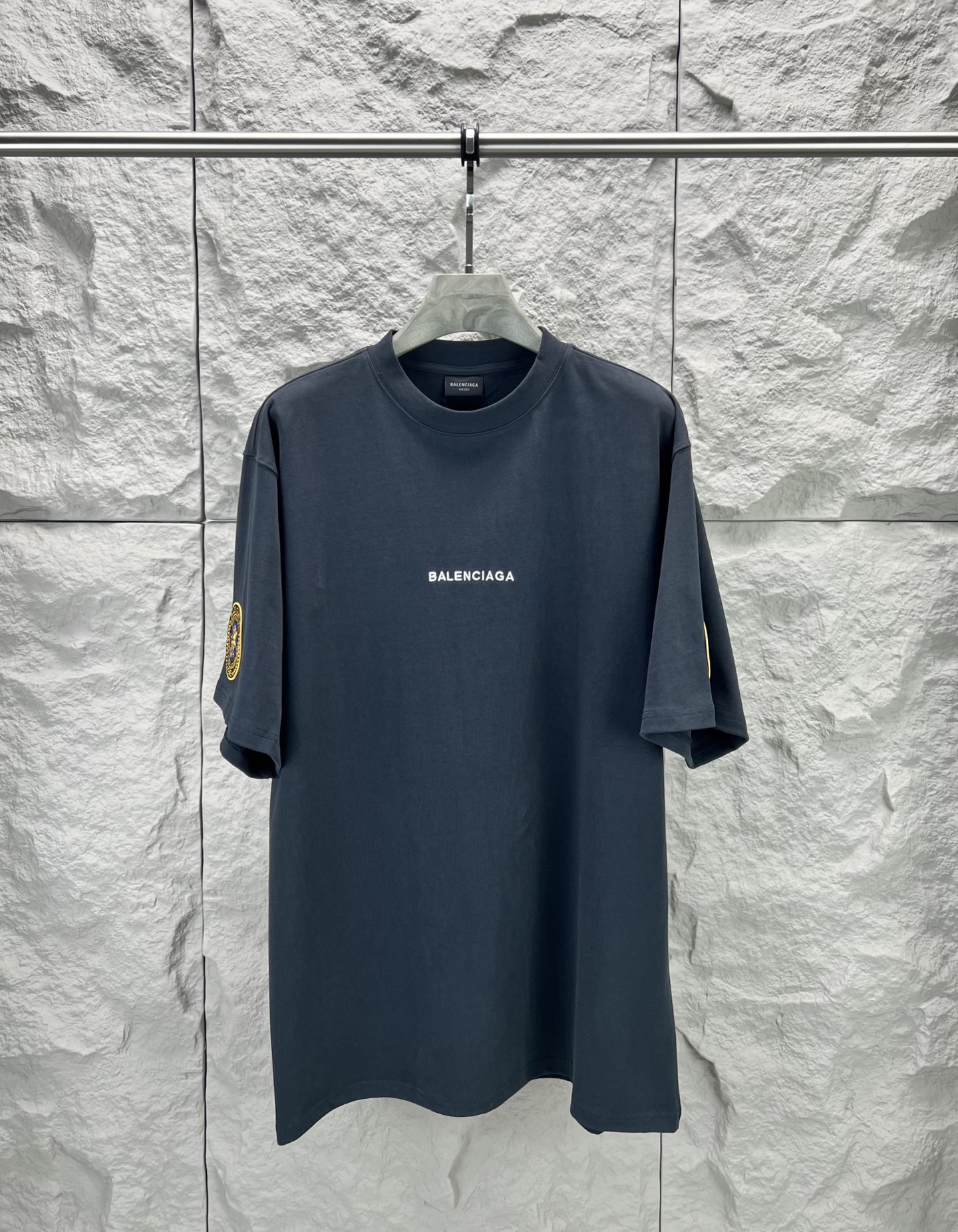 Vetements 胸前字母狮标徽章短袖280克精棉平纹面料 双纱拉架罗纹 平纹纯棉面料是一种高质量的棉纺织品 具有紧密的纺纱技术和高支数 这种面料具有柔软 舒适 透气和吸湿性好等特点 同时其纺织工艺要求也较高 纯棉质织物组织结构为平纹 面料的织物表面平整细腻 质地紧密 具有良好的吸湿透气性和舒适性 能够保持干爽舒适 由于其紧密的纺纱工艺 徽标刺绣章仔点缀 徽标采用进口定做绣线具有光泽感的丝光绣线进行定染 精细的细节处理 造就了立体微浮雕的刺绣效果 哑光挨针刺绣工艺是一种刺绣技术 颜色一致无色差 能与同款搭配营造 造型 驾驭各种场合 定制辅料 三标齐全